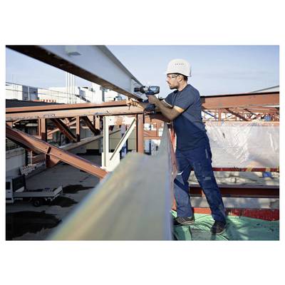 Bouwvakker met helm die een elektrische boormachine gebruikt om stalen balken op een gebouwframe te installeren.