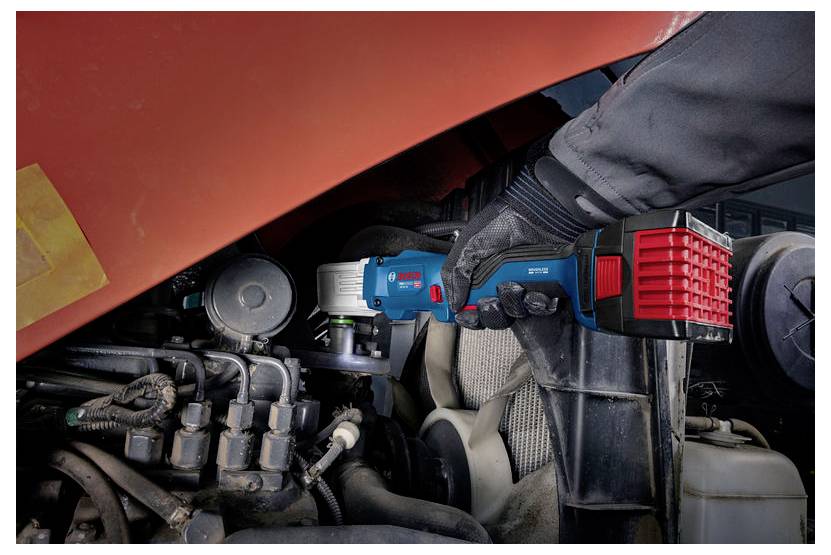 Gehandschoende werker gebruikt een blauwe draadloze elektrische gereedschap om machines in een motorcompartiment van een voertuig te repareren.