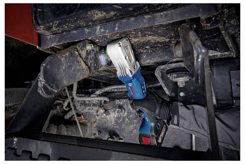 Werknemer die een accu-slagmotor gebruikt om een bout onder een zwaar voertuigchassis los te draaien