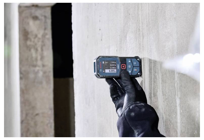 Behandelde hand gebruikt een digitale vochtmeter op een muur om vochtigheid of waterschade te controleren.