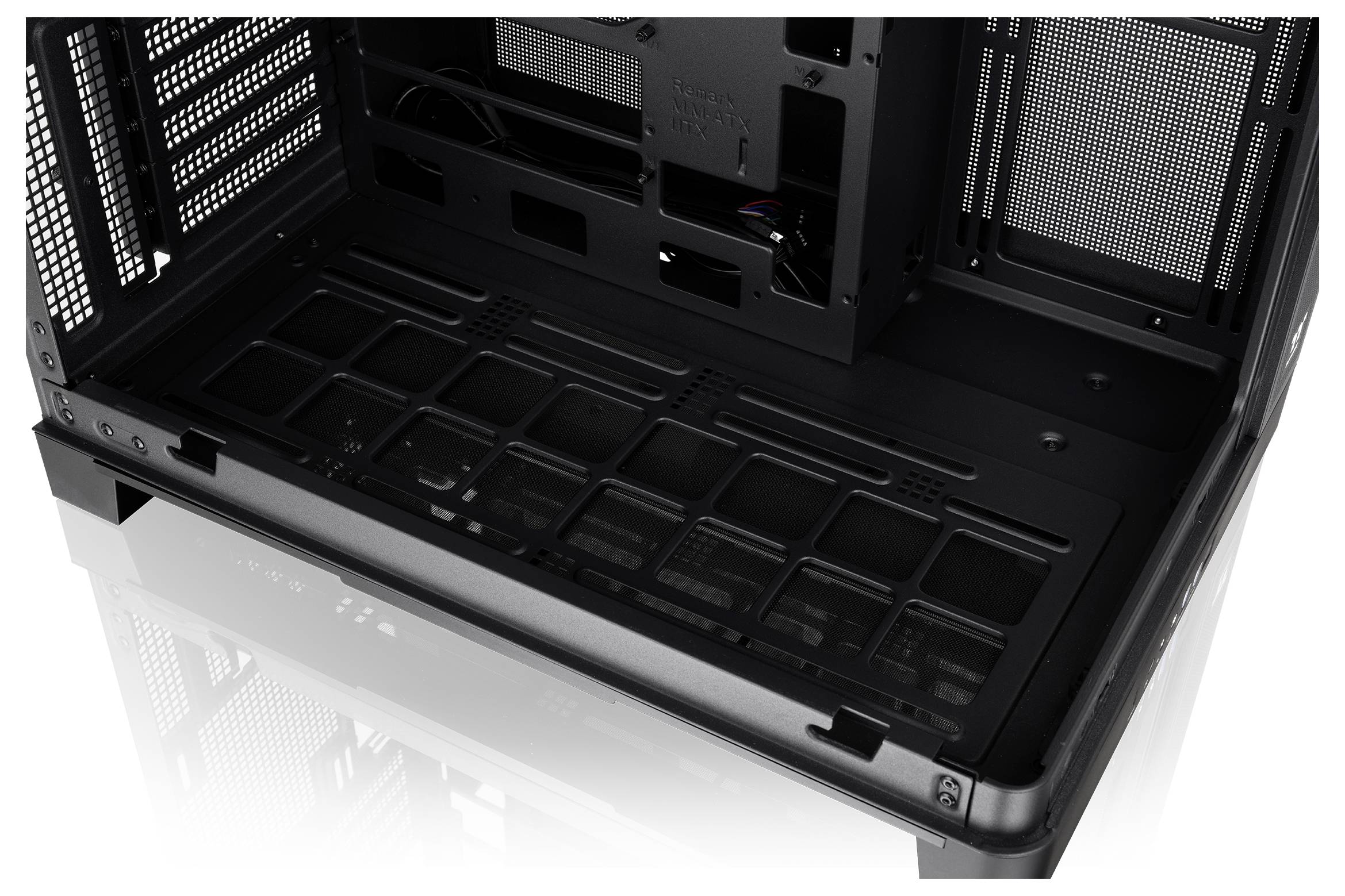 Vergrote weergave van het interieur van een zwarte desktopcomputerkast, met zicht op het lege moederbordblad, schijfschachten en kabelrouteringsopeningen.