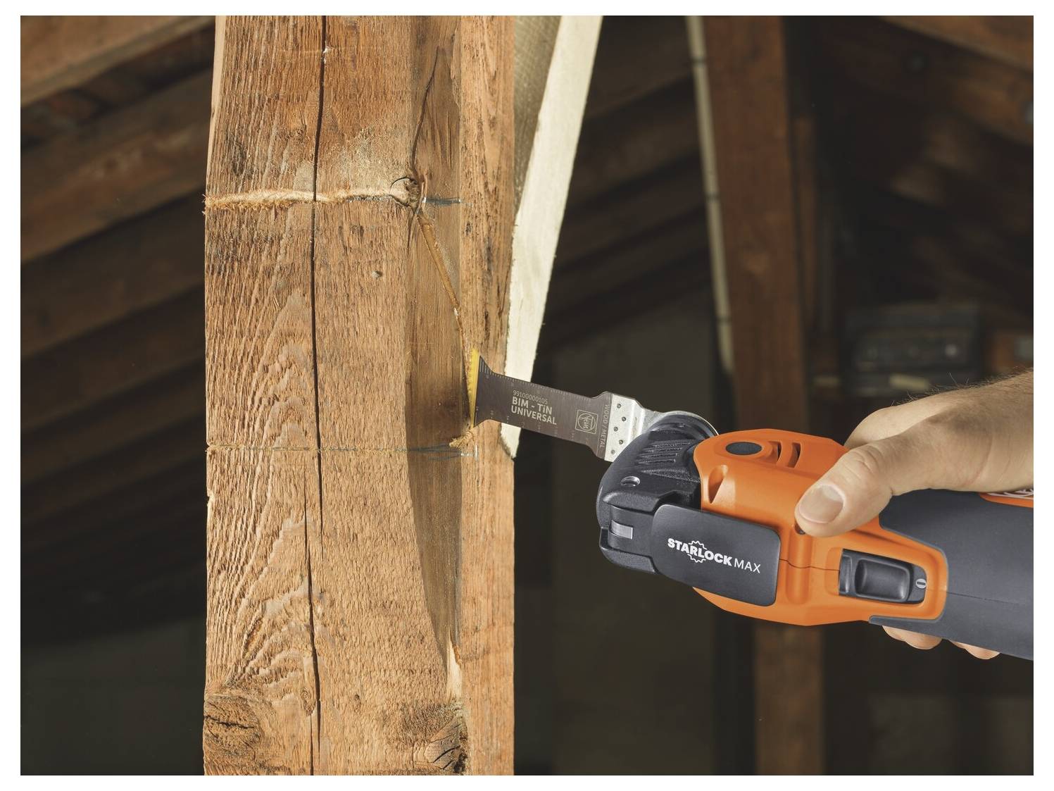 Hand die een oranje reciprocerende zaag gebruikt om in een houten balk binnen een structuur in te snijden.