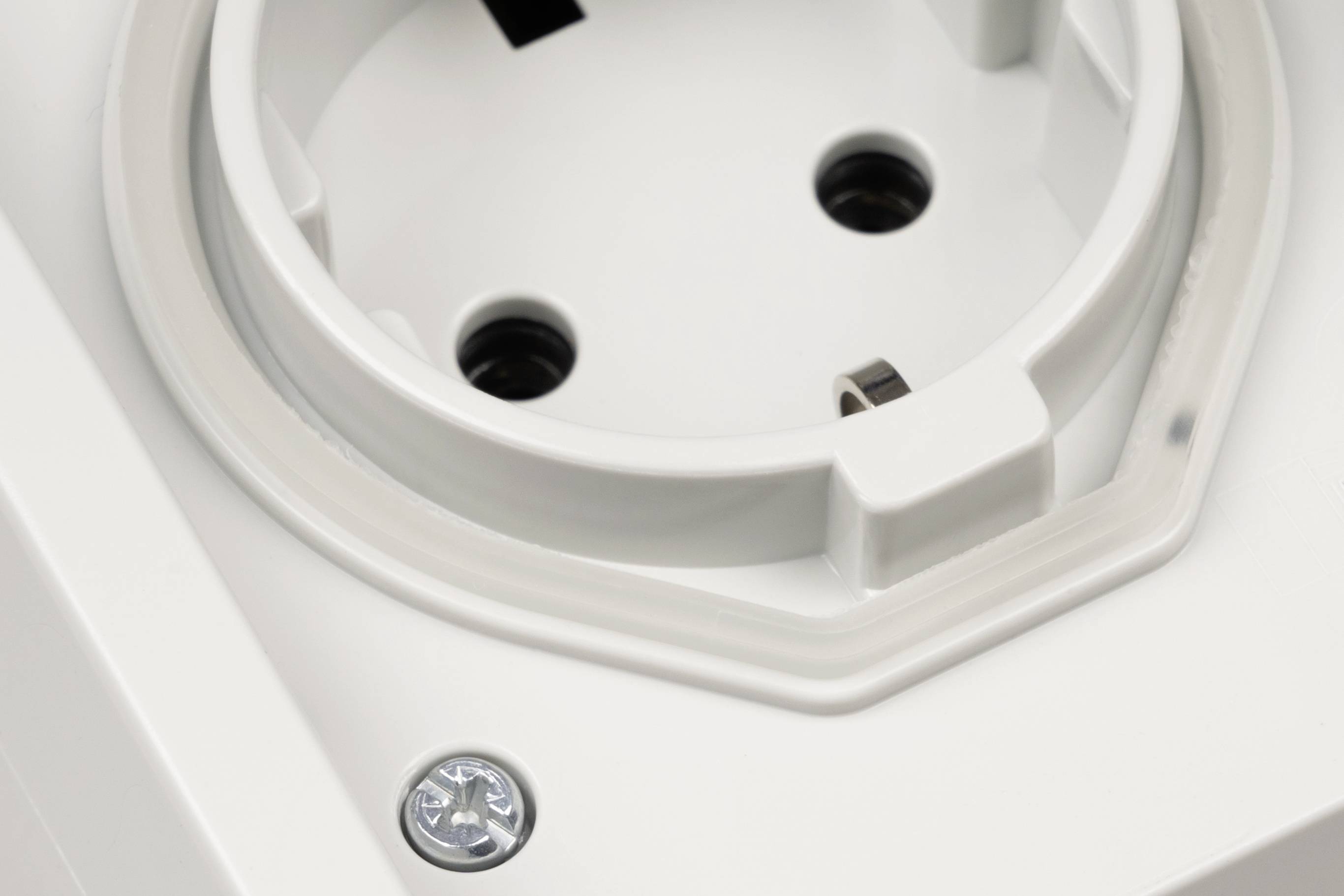 Close-up van een wit elektrisch stopcontact met twee ronde contactgaten en een zichtbare schroef op de frontplaat.