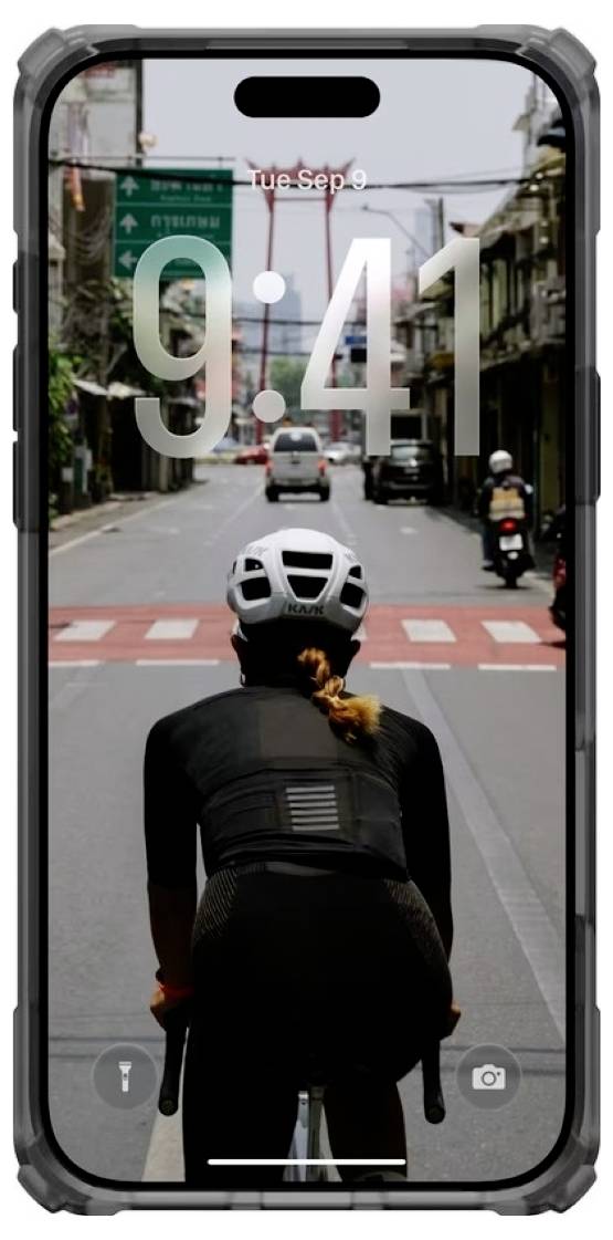 Wielrenner van achteren gezien op een stadsstraat om 9:41, met het telefoonvergrendelingsscherm dat de tijd over de scène toont.