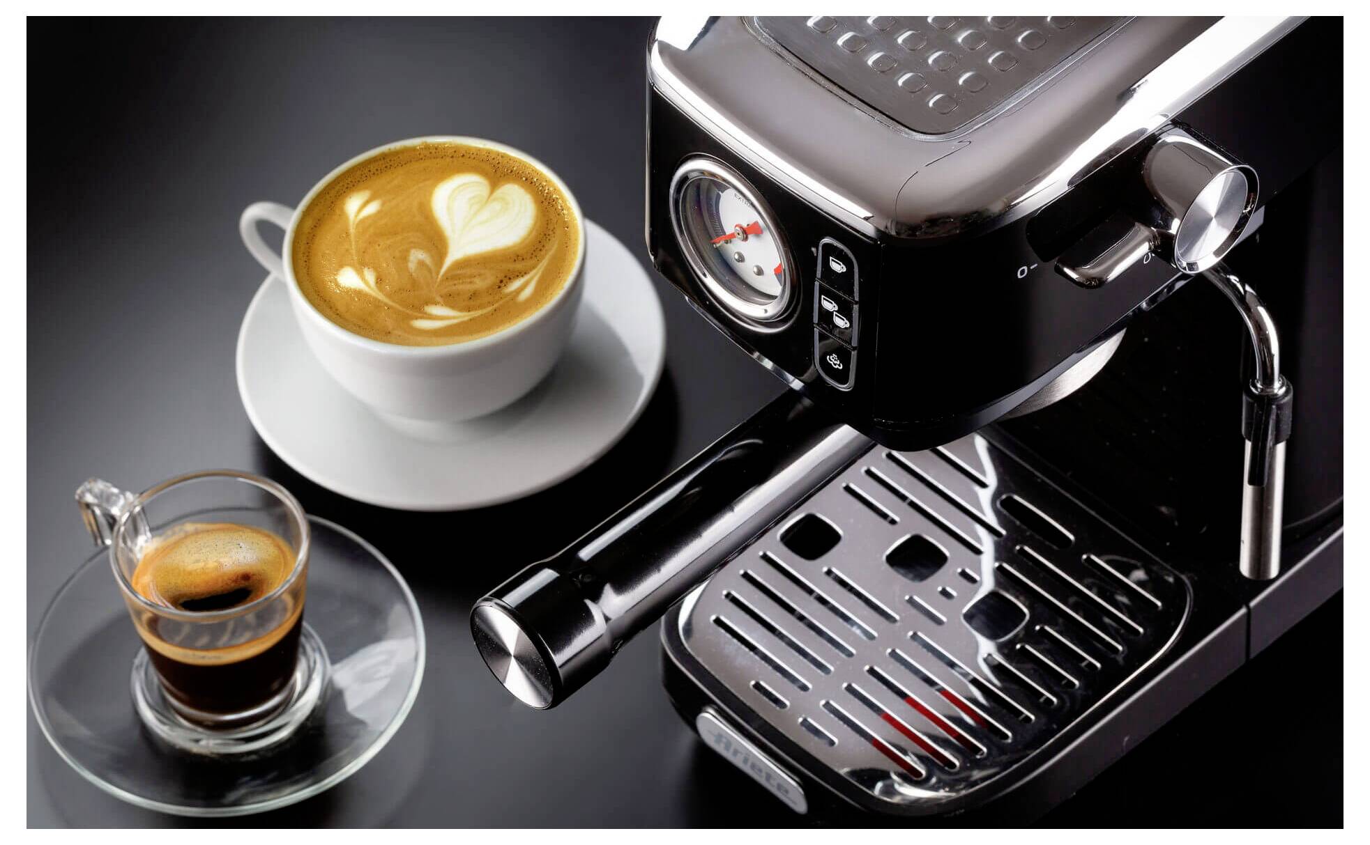 Espressomachine met een kopje latte art en een klein glaasje espresso op een schoteltje, weergegeven op een donker werkblad.