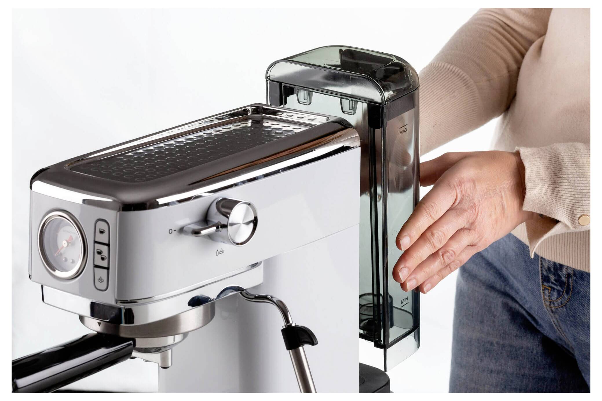 Een persoon die een watertank in een zilveren espressomachine plaatst en deze voorbereidt voor gebruik.