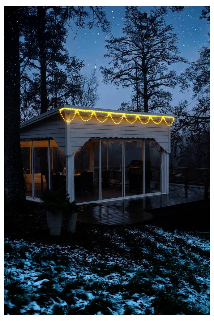 Kleine hut of zonkamer in de schemering, omlijst met warme slingerlampen en grote ramen, gelegen in een sneeuwbewerkt bosrijke tuin.