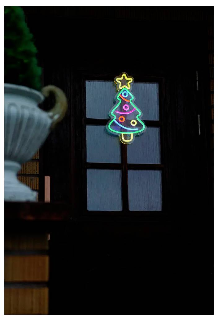 Neon kerstboomdecoratie die 's nachts in een raam gloeit, met een ster bovenop.