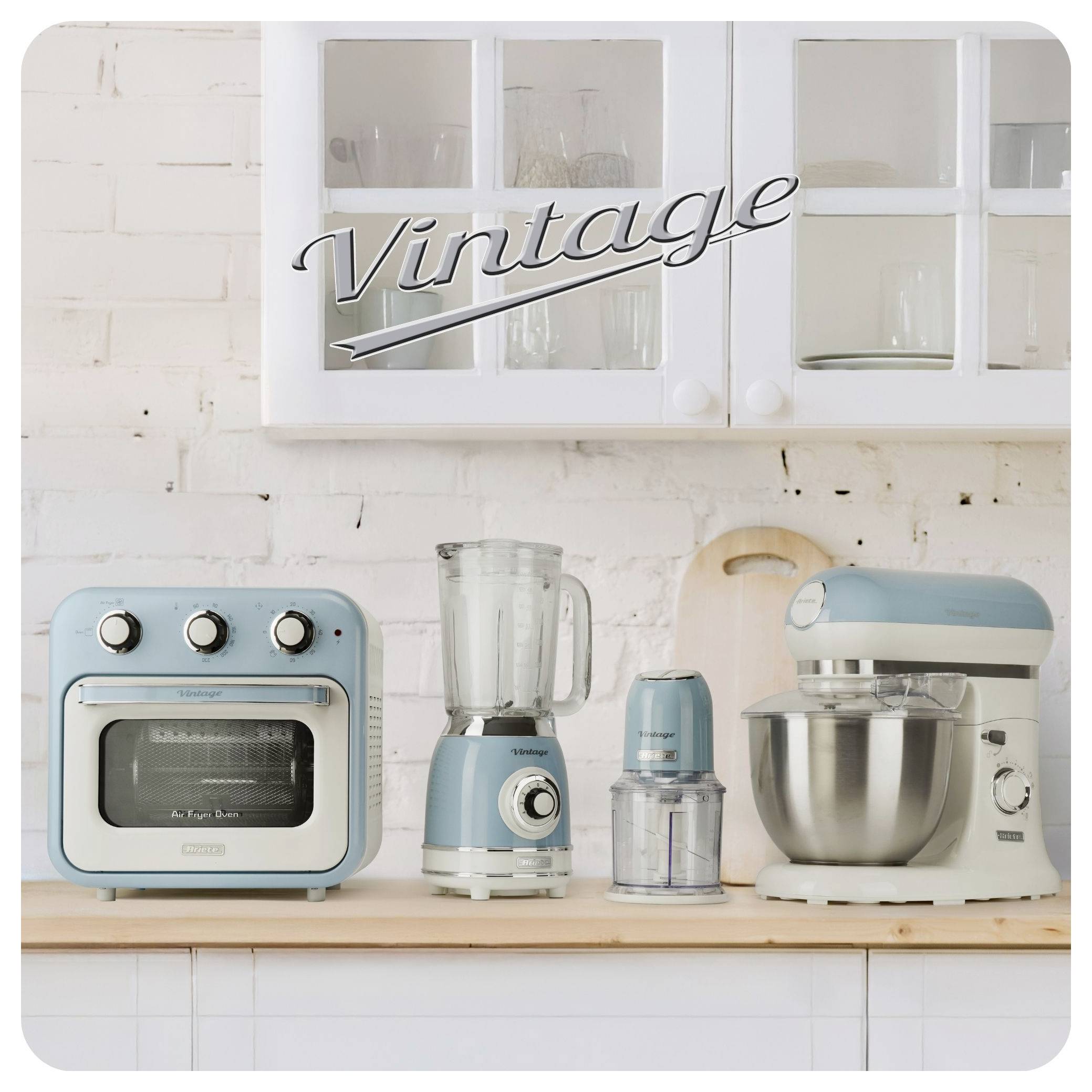 Retro-stijl blauwe keukenapparaten op een rij op een aanrecht onder een kast, waaronder een broodrooster, een blender, een molen en een staande mixer.