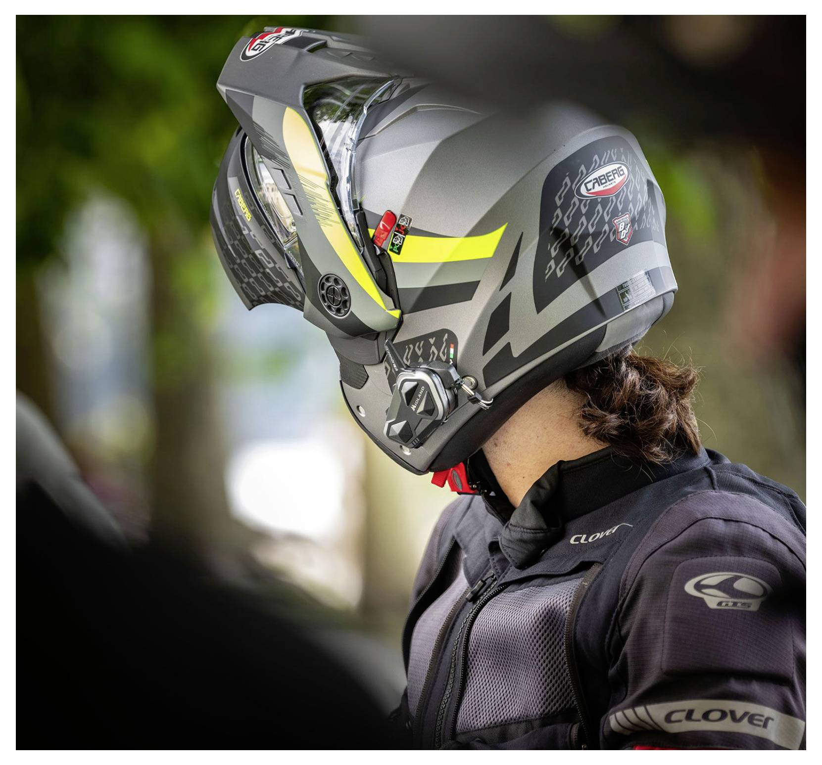 Motorrijder met een zwarte integraalhelm en beschermend jack, afgebeeld in zijaanzicht buiten.