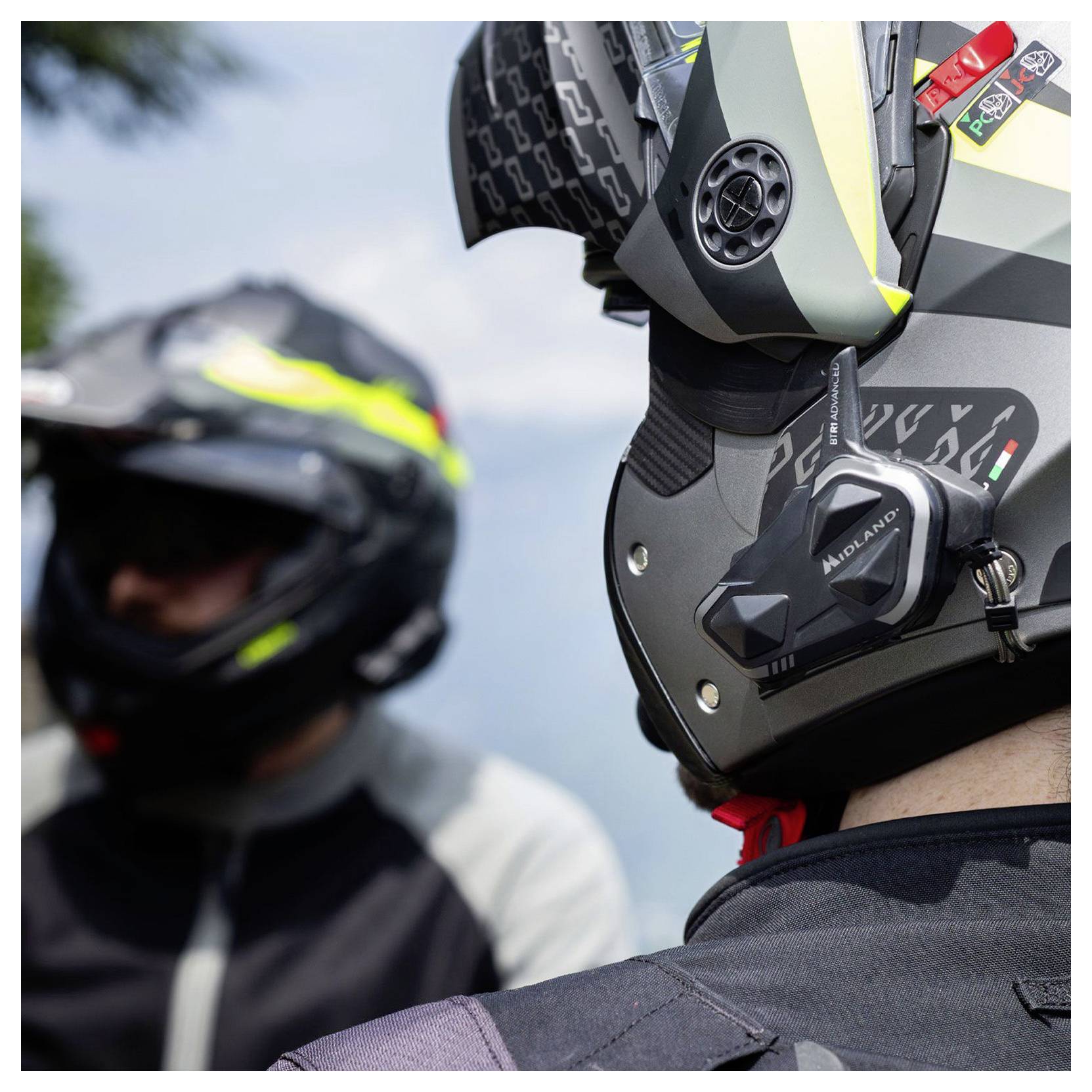 Close-up van een motorrijder die een zwart-grijs integraalhelm draagt met een bevestigde camera, met een ander voertuig wazig op de achtergrond.