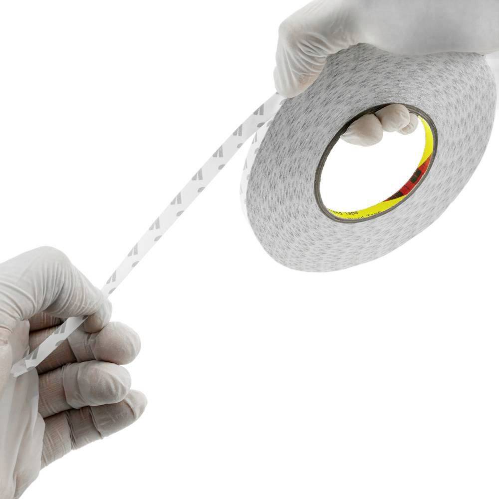 Gehandschoende handen trekken een strook reflecterende zelfklevende tape uit een rol op een witte achtergrond.