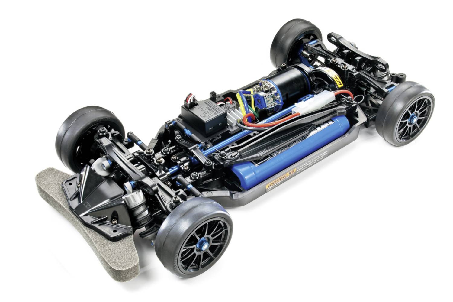 Blootgestelde chassis van een radiografisch bestuurd raceauto met vier wielen, blauw accupakket, motor, elektronica en voorkantslot op een witte achtergrond.