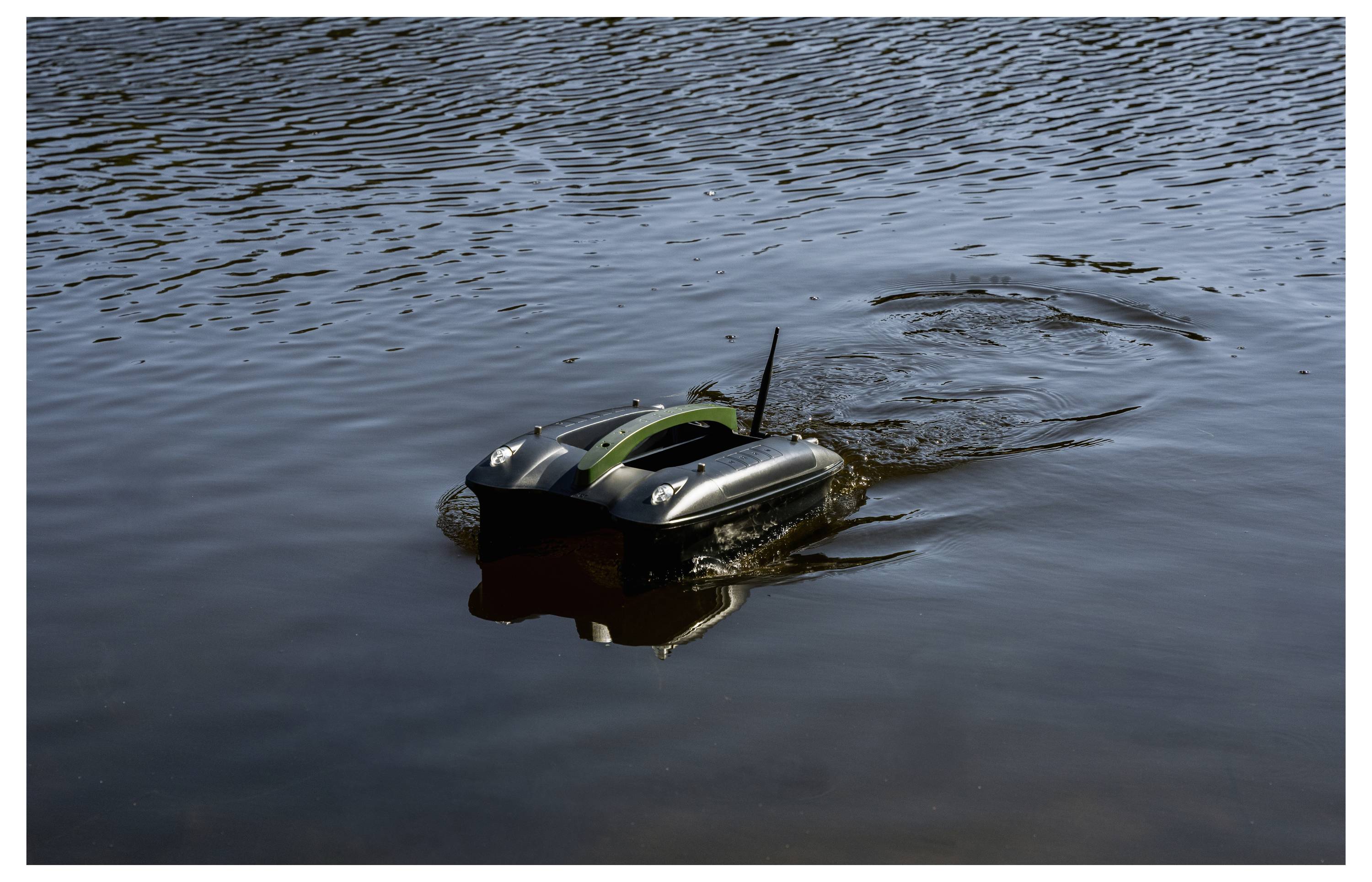 Klein op afstand bestuurd bootje dat op kalm water drijft en rimpelingen achter zich achterlaat.