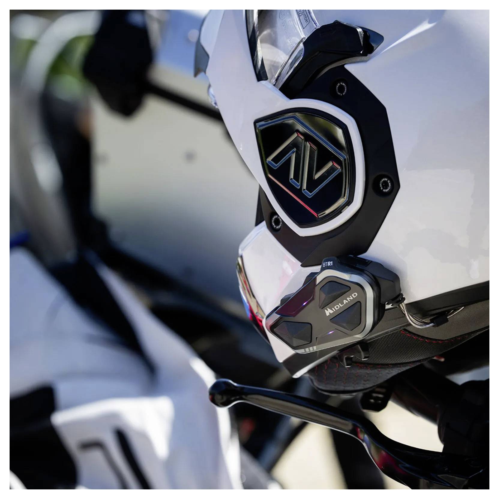 Close-up van een witte motorhelm met gemonteerde zwarte Midland communicatieapparatuur, met zicht op het zijprofiel van de helm en het viziergebied.