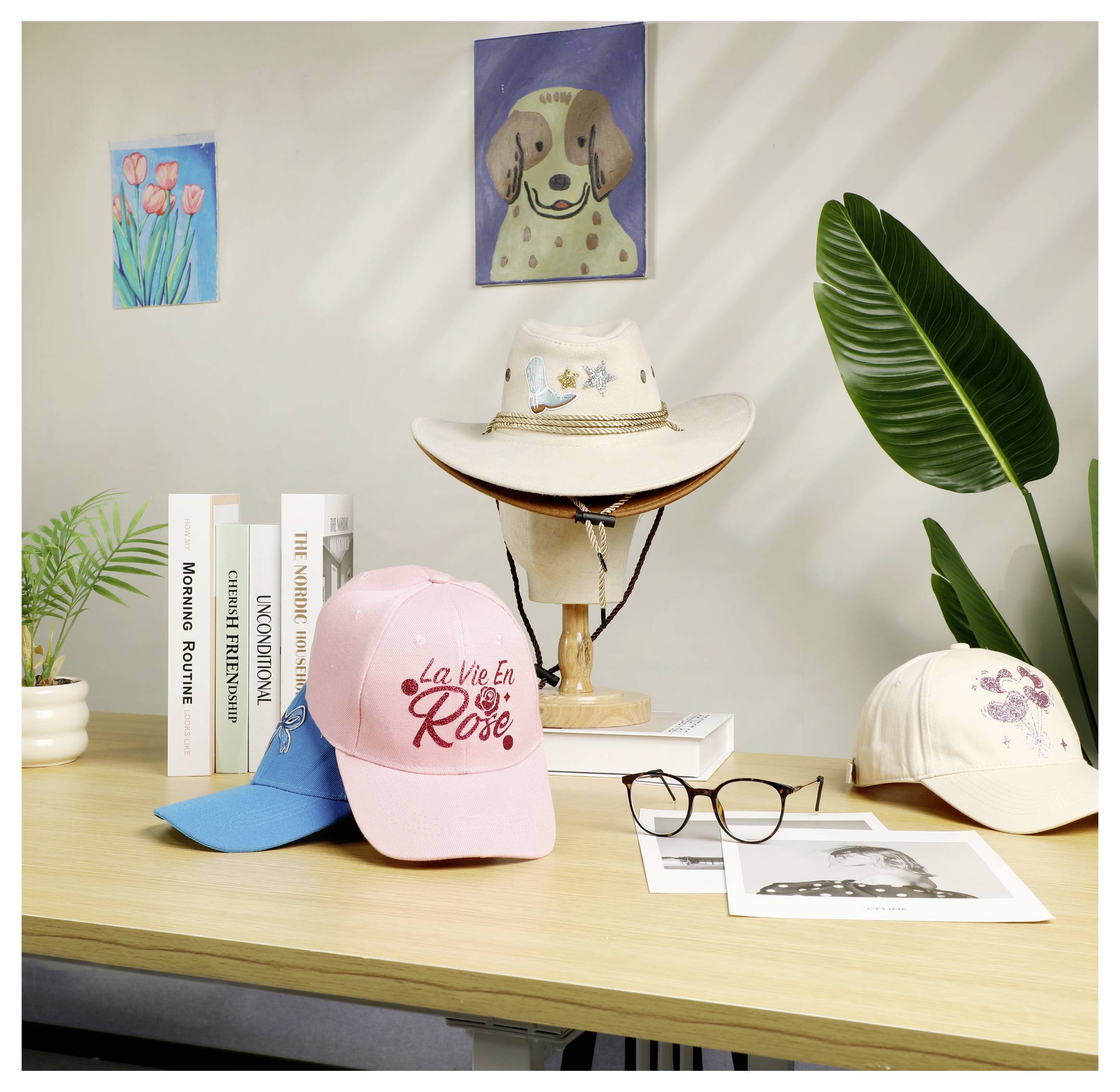 Weergave van assorteerde hoeden en brillen op een houten bureau, met boeken, planten en kleine wandkunst op de achtergrond.