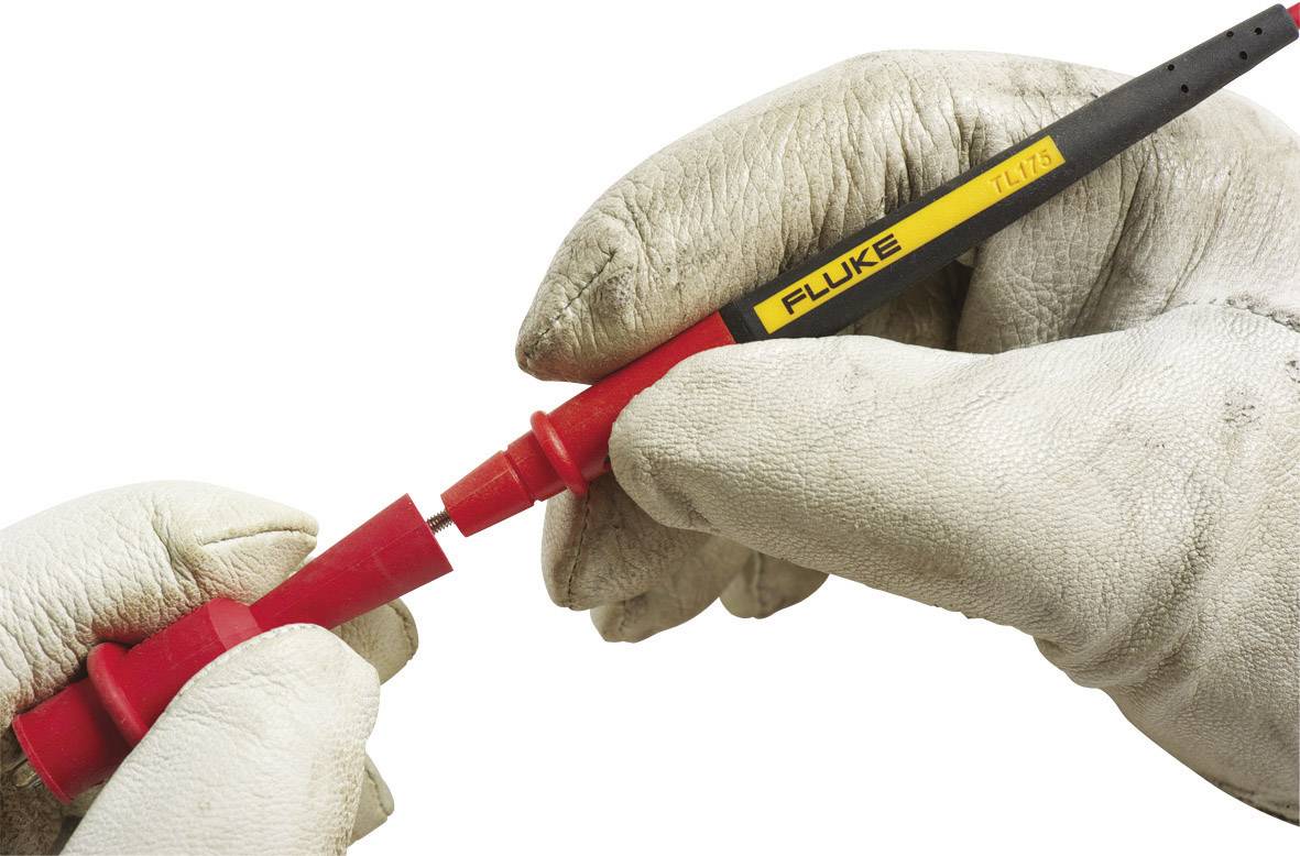 Een persoon met handschoenen houdt een rode spanningzoeker-schroevendraaier met 'FLUKE' markering, klaar voor contactcontrole.