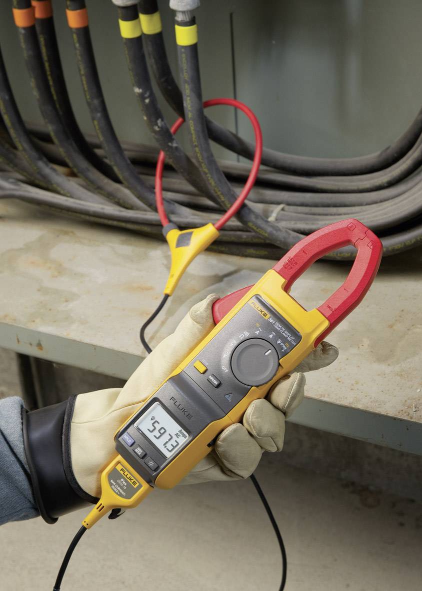 Een persoon meet de spanning van een kabel met een geel-rood multimeter in een elektrische installatie. Het display toont '39,13'.