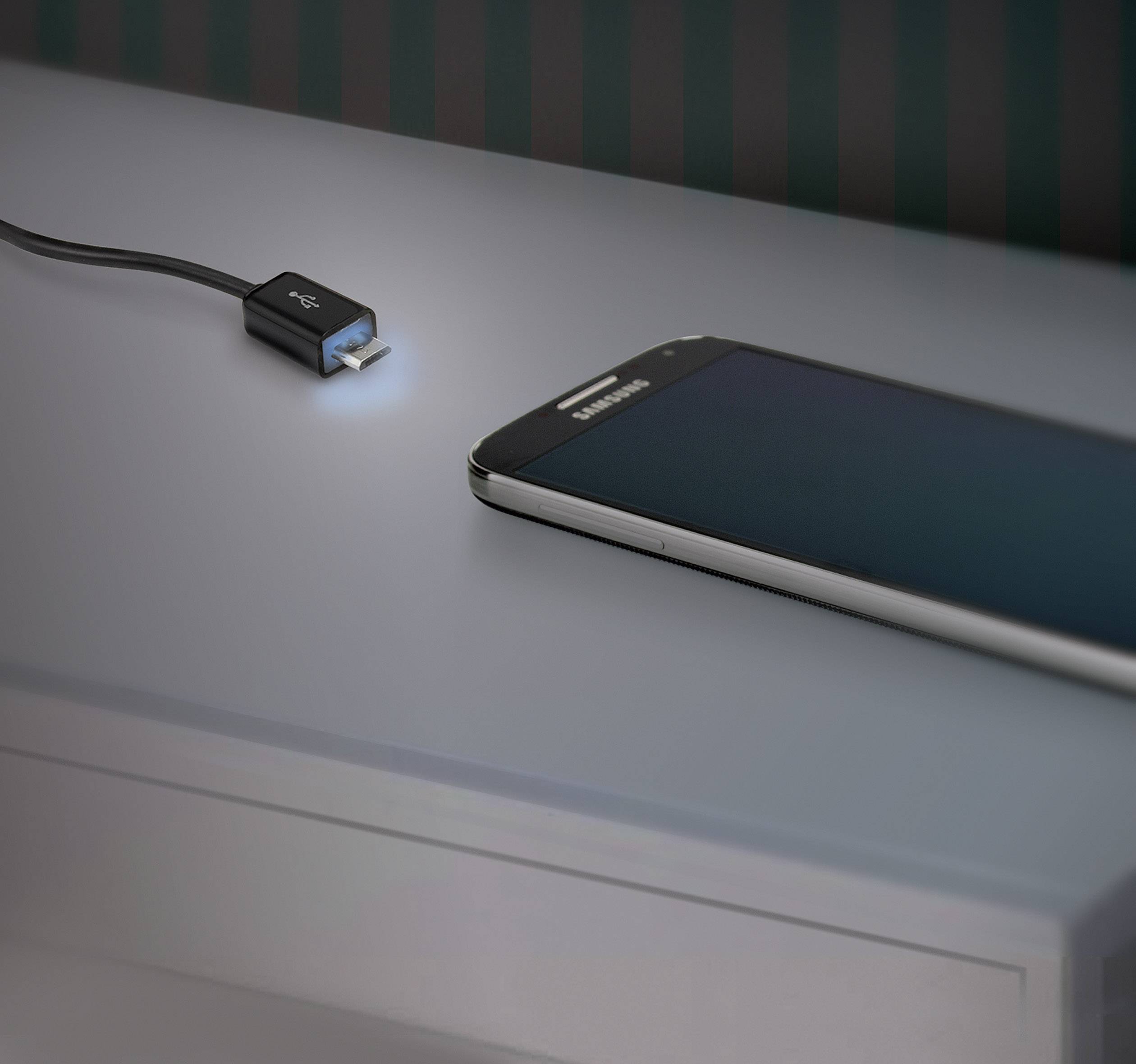 Een smartphone ligt op een tafel naast een oplichtend USB-kabel dat klaarstaat om het apparaat op te laden.