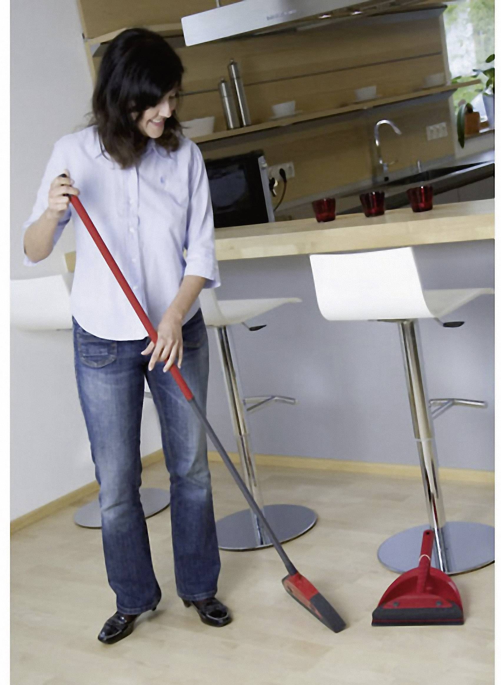 Een persoon veegt de vloer in een moderne keuken, glimlachend.