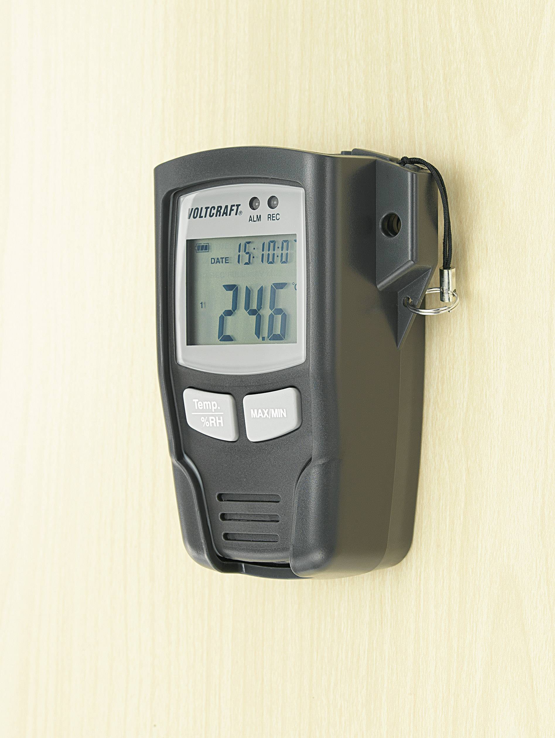 Een elektronische thermometer van Voltcraft geeft de temperatuur aan van 24,6 graden Celsius. Hij is bevestigd aan een houten muur.