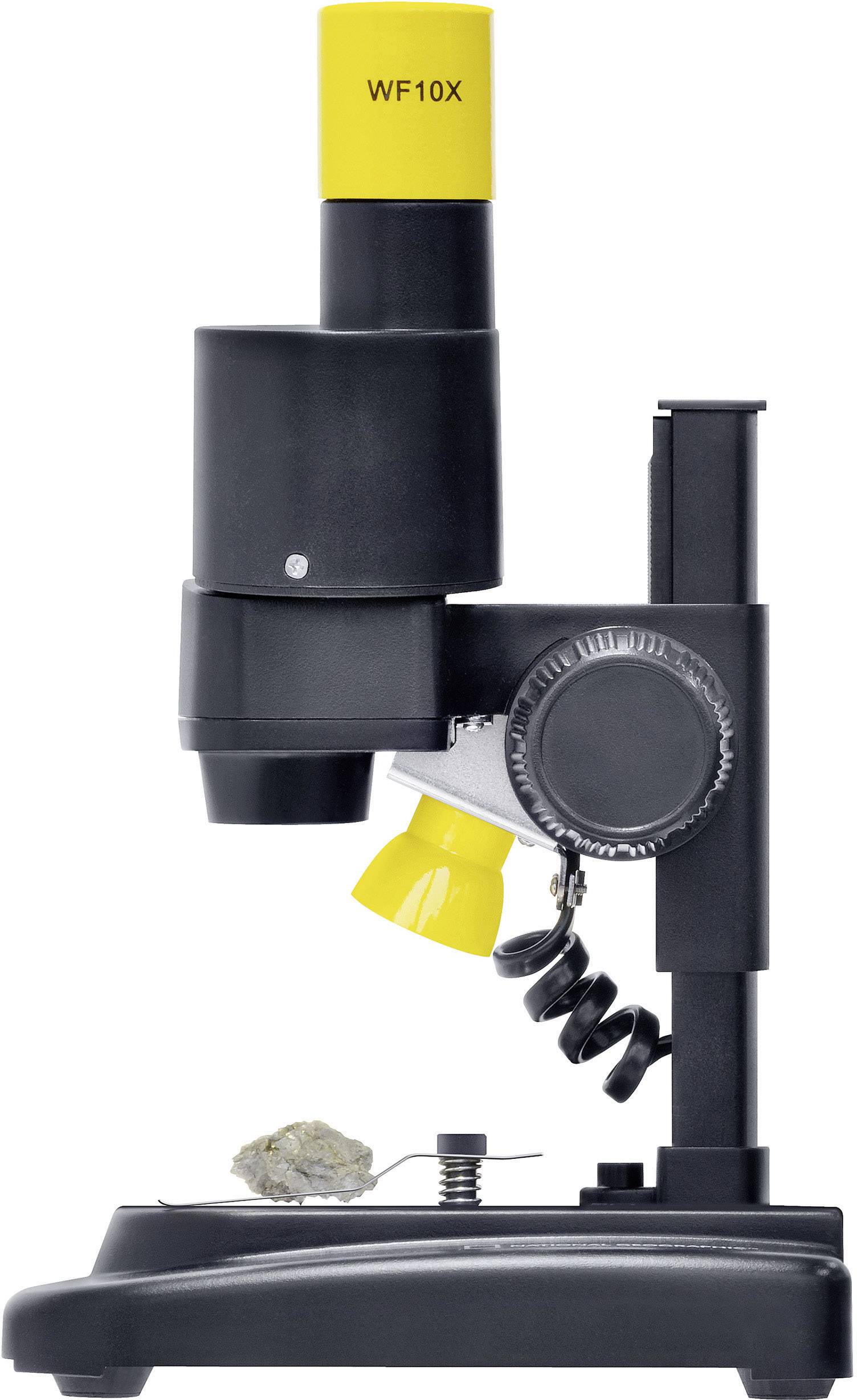 Een zwarte microscoop met een gele lens, gezien van opzij, op een tafel. Onder de lens bevindt zich een klein object om te bekijken.