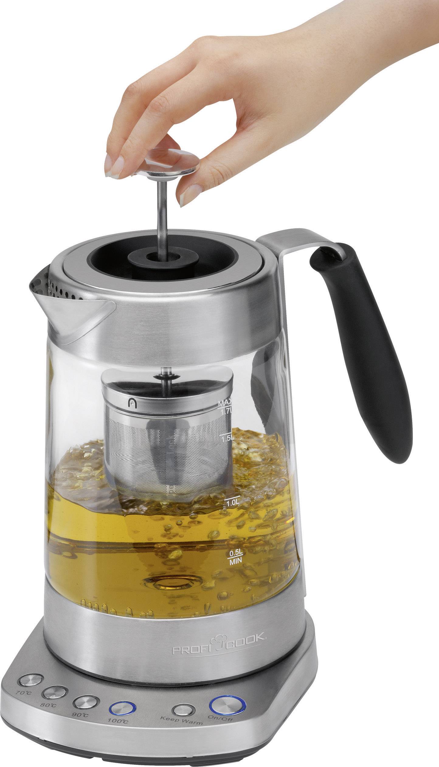 Elektrische waterkoker met geïntegreerde theepot, een hand drukt de knop naar beneden. Bevat theezeef met gele thee.