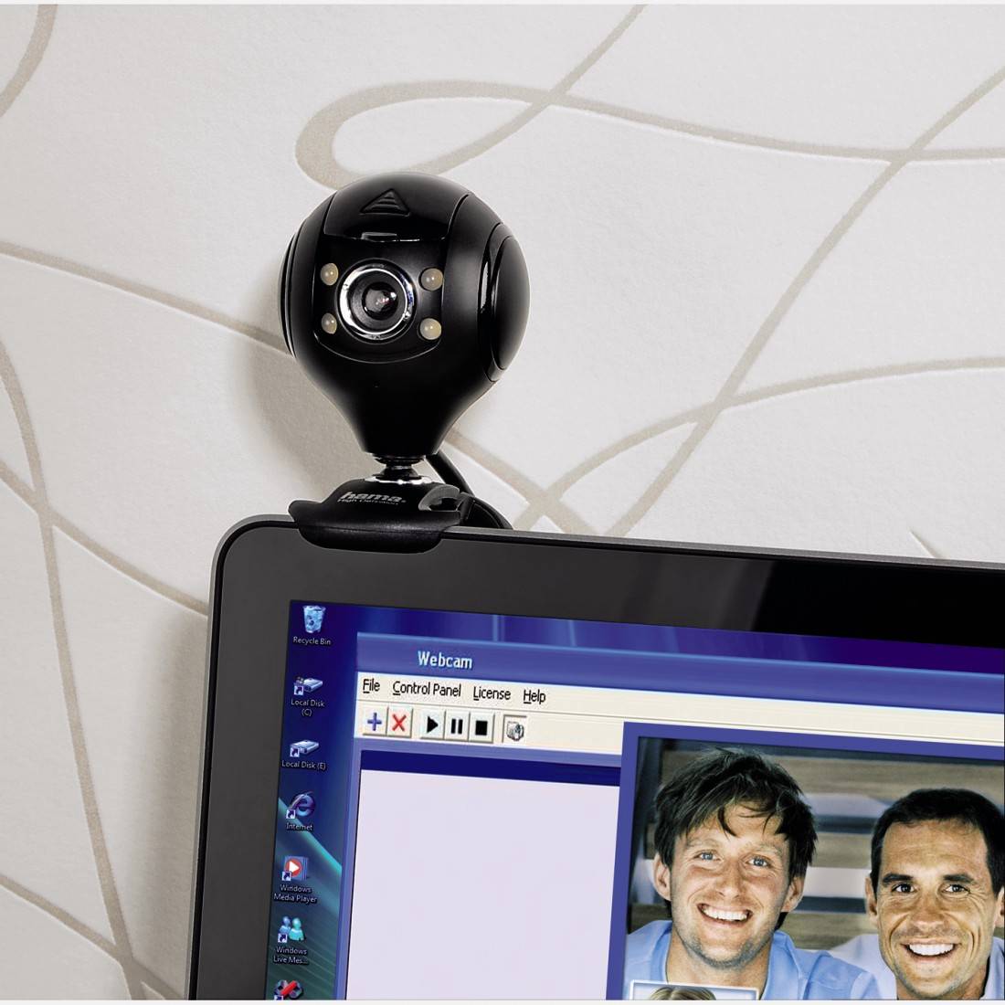 Een webcam is gemonteerd op een laptopscherm waarop een videobelprogramma is geopend met twee lachende personen.