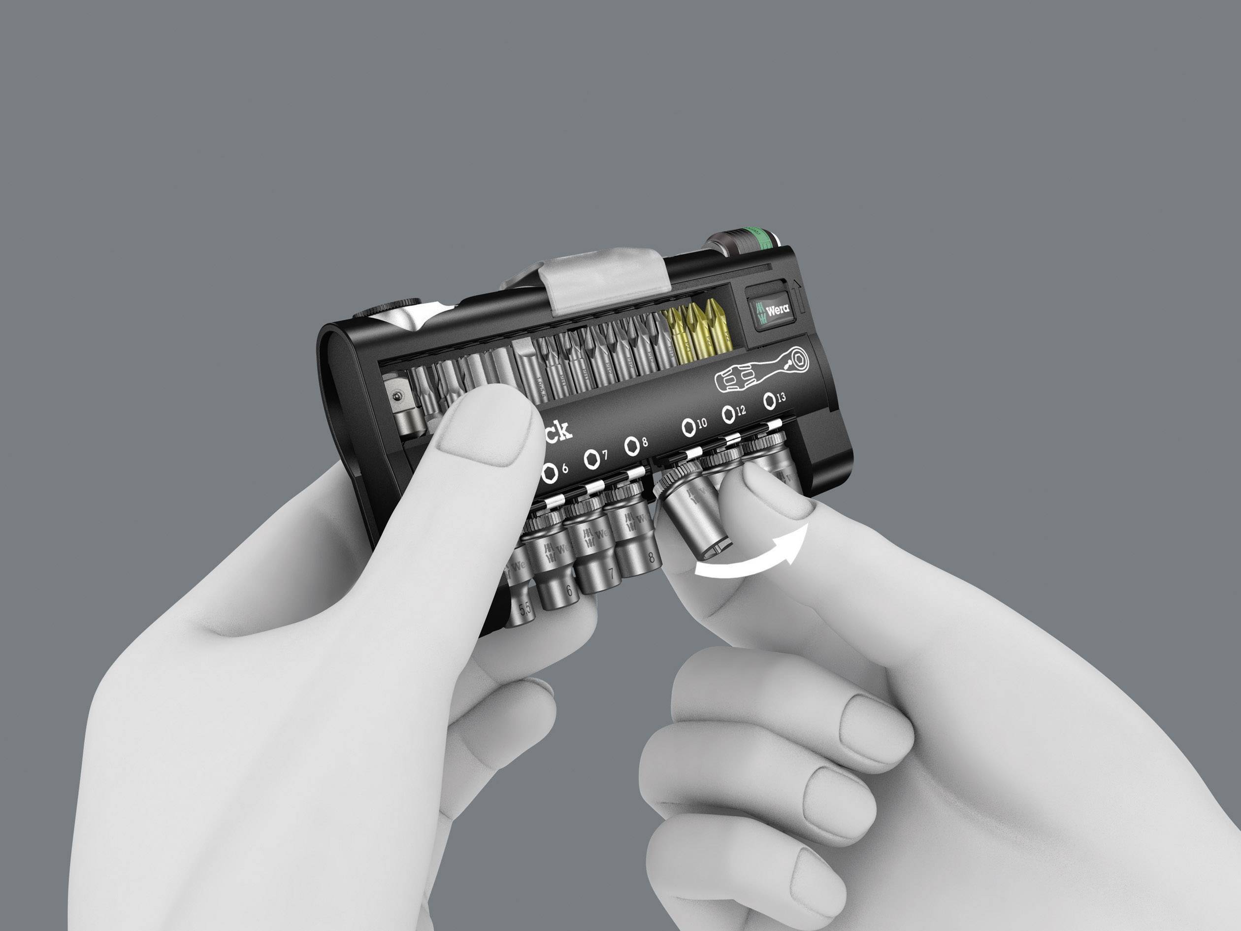 Twee handen houden een compact schroevenset vast. Een hand trekt een gereedschap uit. Het set bevat verschillende bits en kleine gereedschappen.