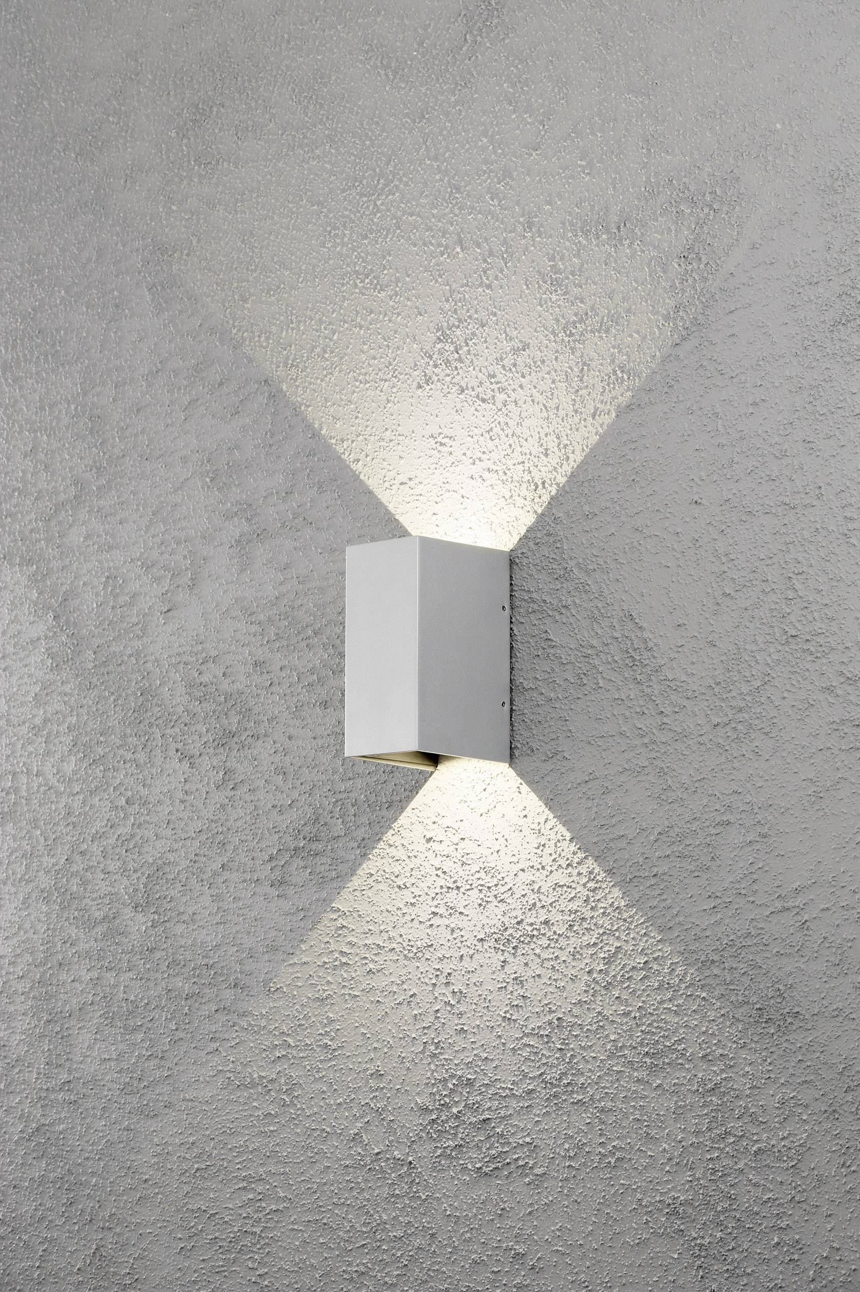 Witte wandlamp aan een grijze gestructureerde muur, met lichtstralen gericht naar boven en beneden.