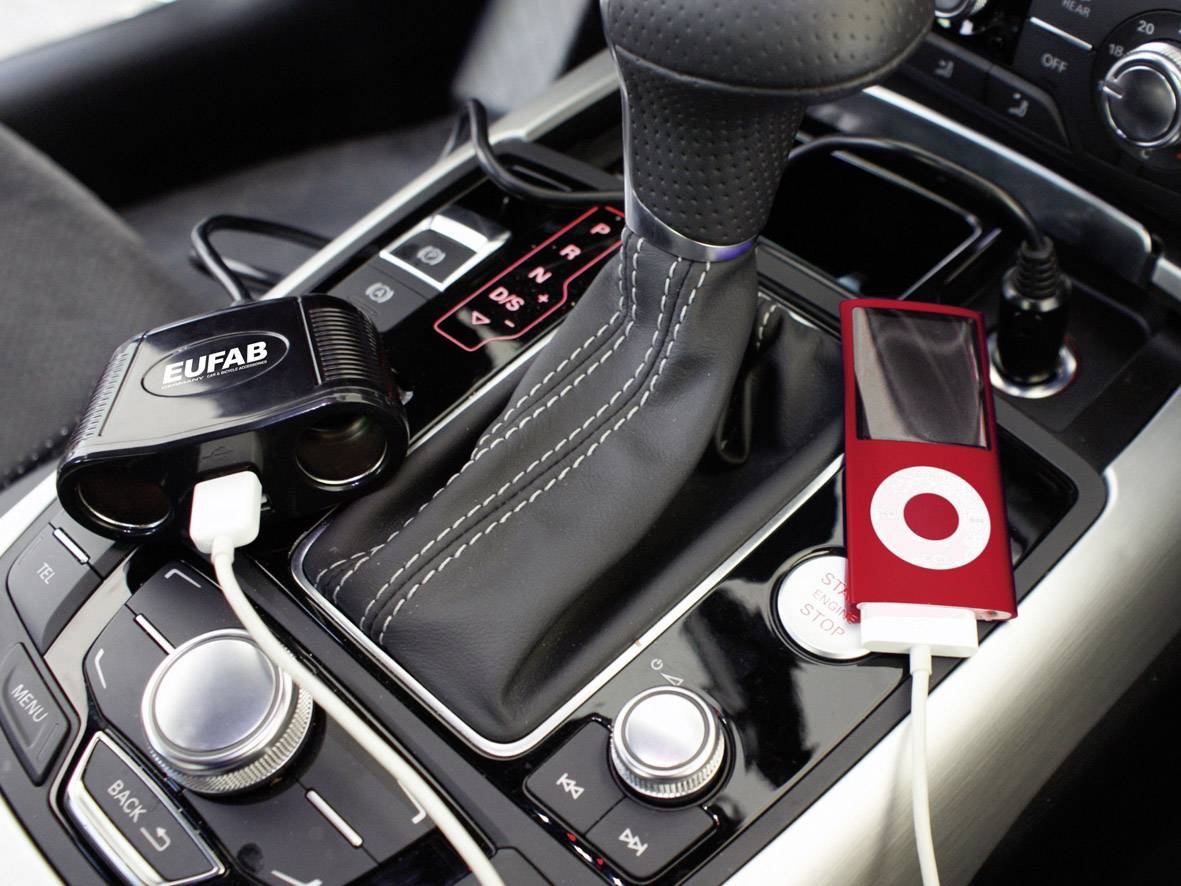 Autodashboard met oplader en een rode MP3-speler die op de oplader is aangesloten.