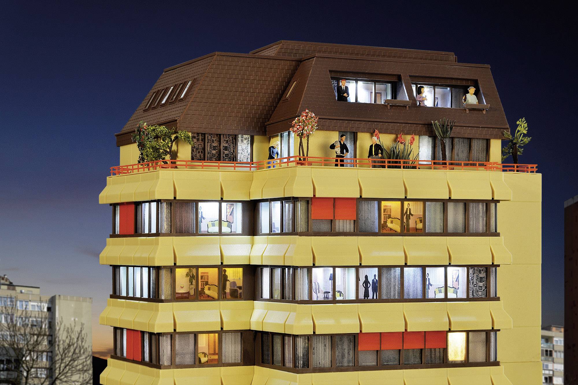 Een meerverdiepingsgebouw 's nachts met verlichte ramen, waarbij verschillende mensen en activiteiten zichtbaar zijn.