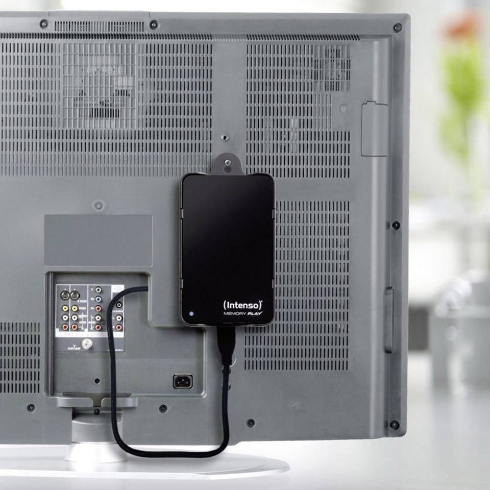 Externe 'Intenso' harde schijf aangesloten aan de achterkant van een monitor, verbonden met bijbehorende USB-kabel.