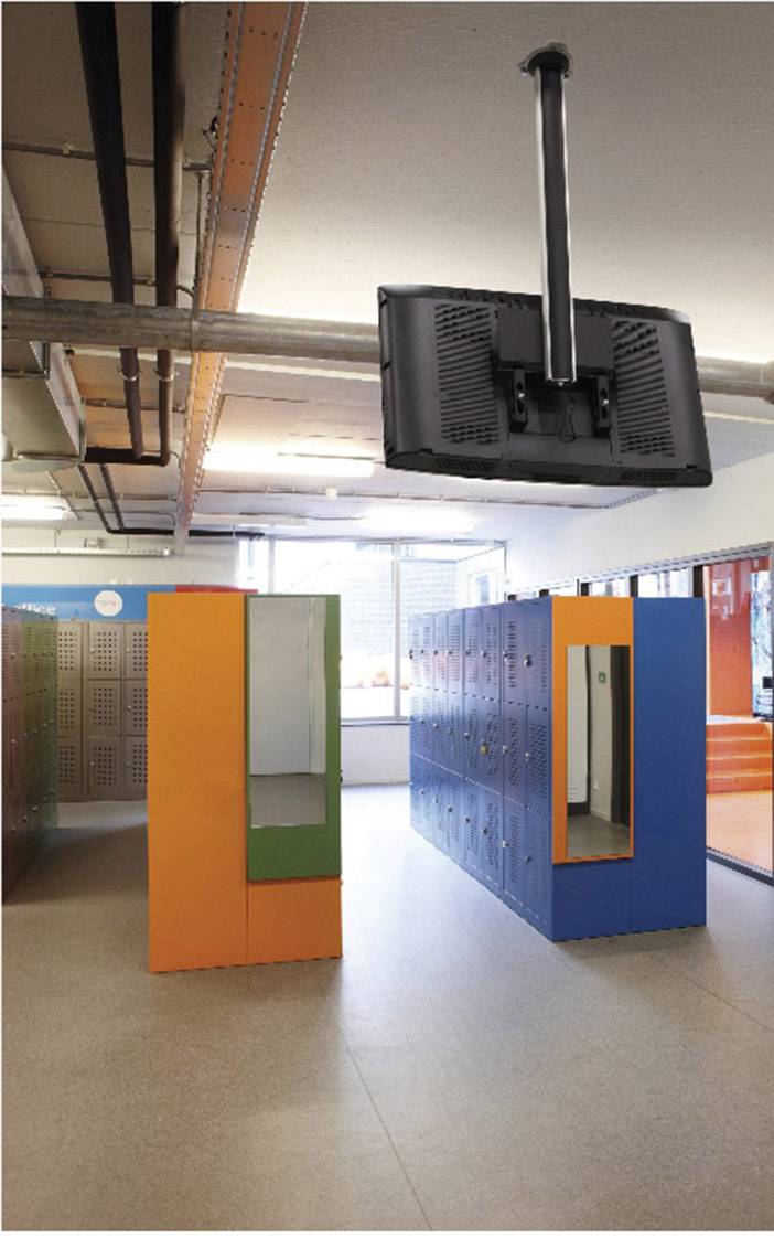 Kleedruimte met kleurrijke kluisjes, moderne verlichtingselementen en een schermhouder die aan het plafond hangt.