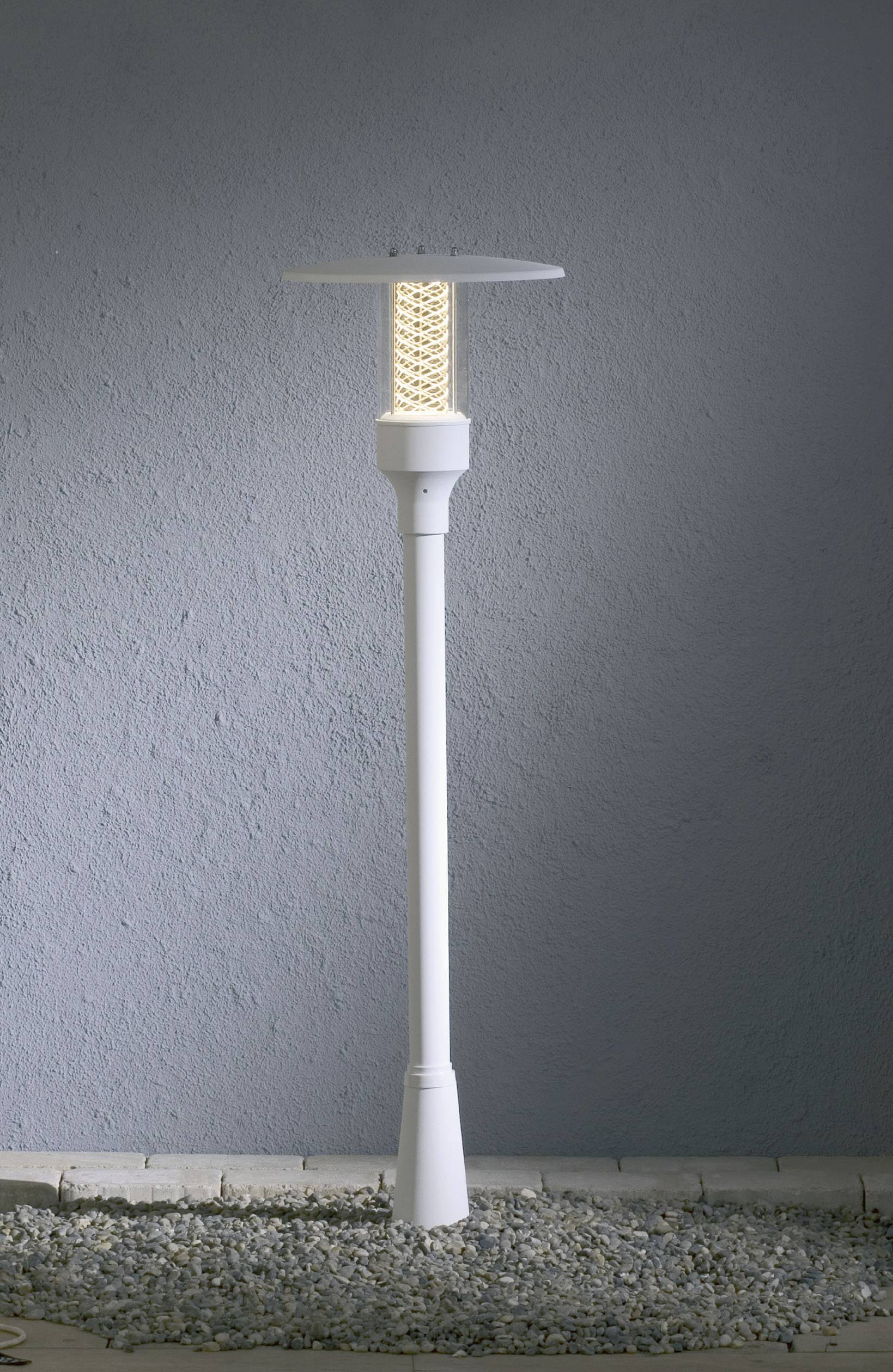 Witte tuinlamp op grind voor een grijze muur, met een modern design en een oplichtend LED-licht in het midden, geschikt voor buitengebruik.