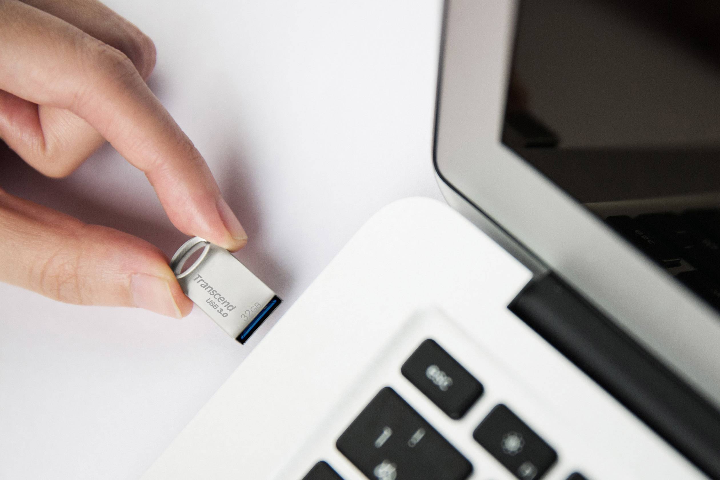 Een hand steekt een USB-stick in een laptop.