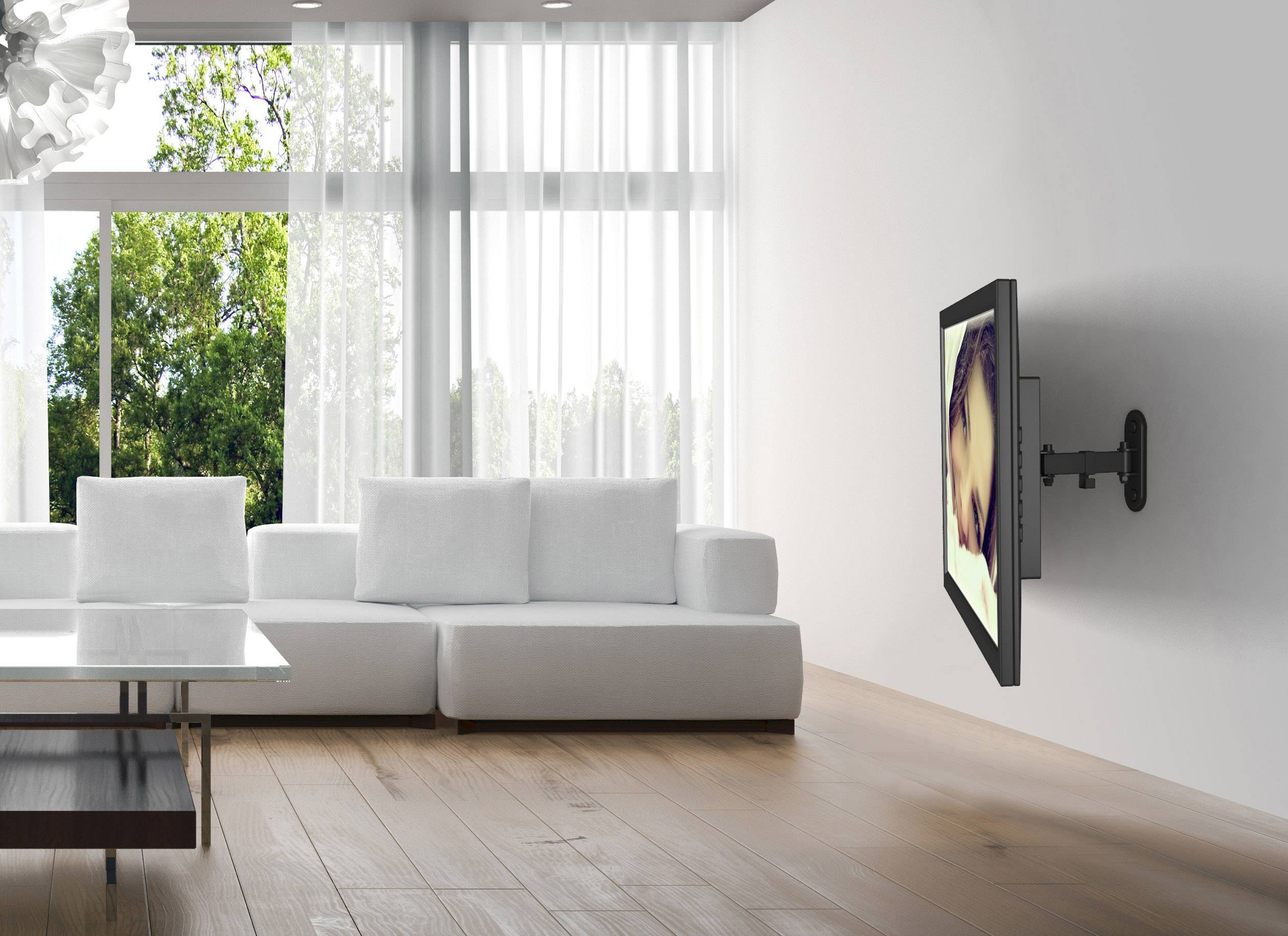 Woonkamer met groot raam, witte bank, houten vloer en een flatscreen-tv aan de muur bevestigd.