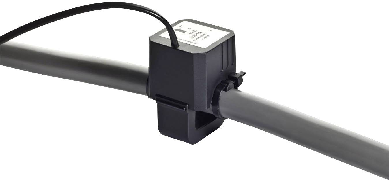 Een zwarte sensor is gemonteerd om een grijze buis. Kabels verbinden de sensor met een apparaat. De sensor meet de doorstroming in de buis.