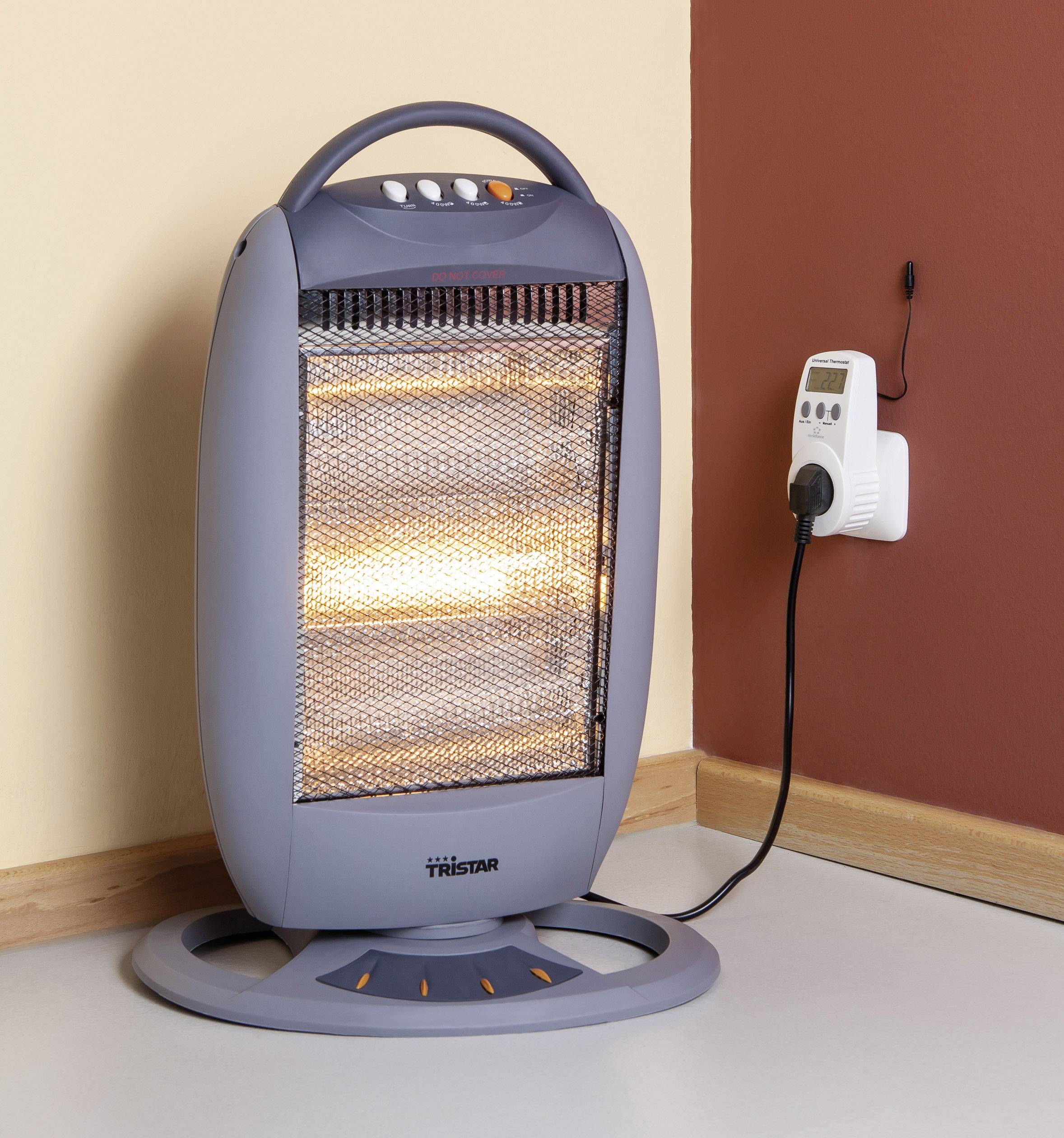 Een elektrische verwarmingsventilator staat aan in een hoek van een kamer en is aangesloten op een stopcontact.