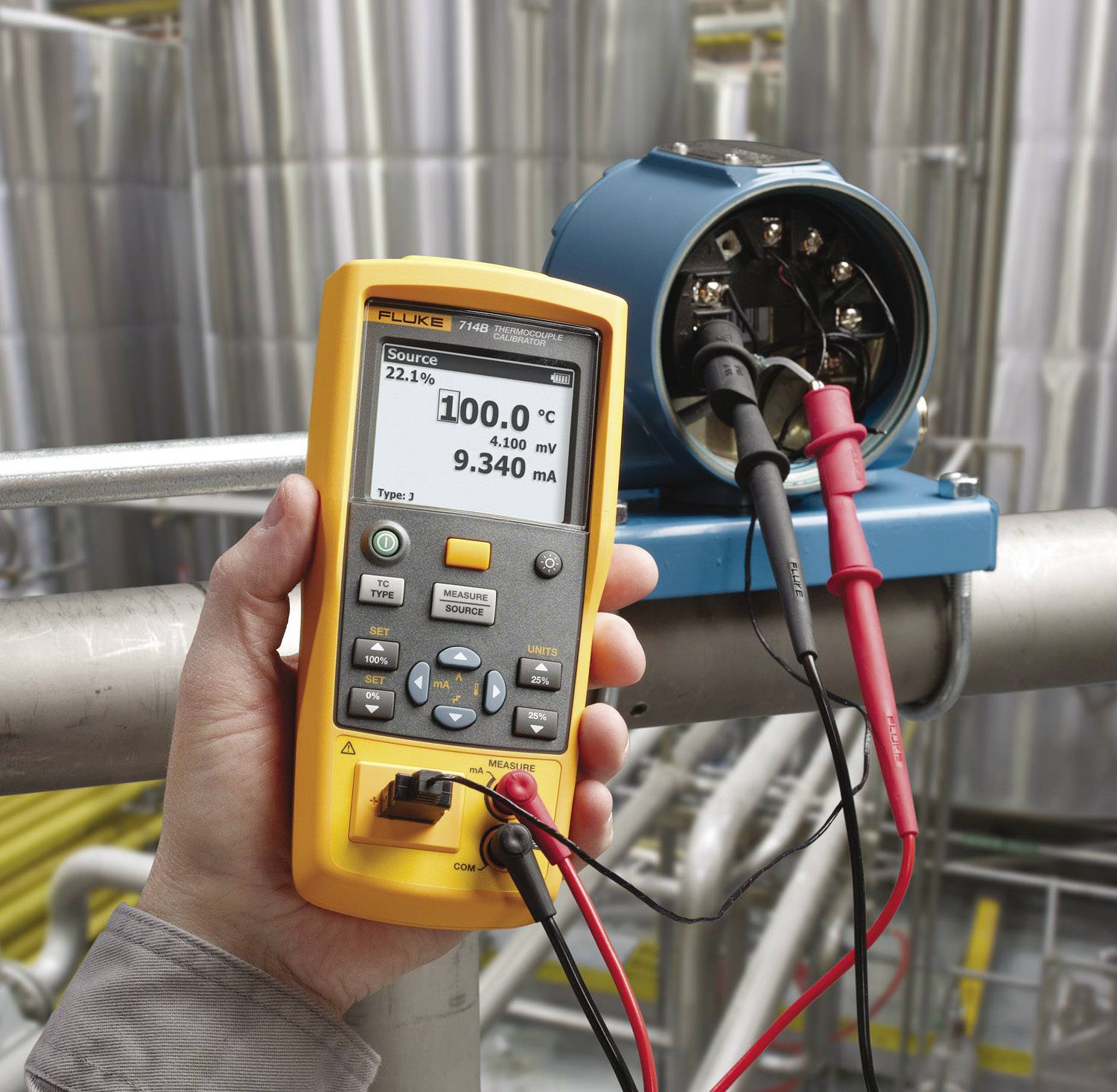 Een persoon houdt een elektrisch meetapparaat vast voor de kalibratie van een sensor. Het display toont temperatuur en stroomsterkte.