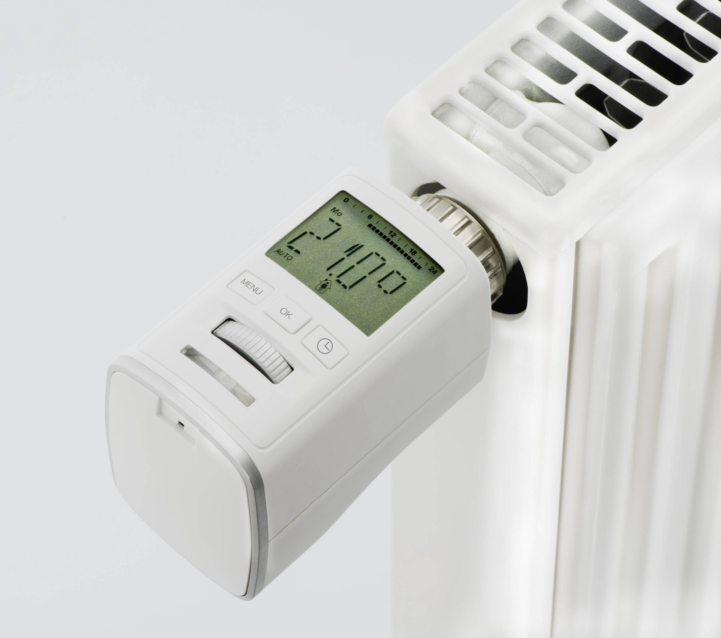 Een digitale thermostaat op een witte radiator toont 24,0 graden Celsius aan.