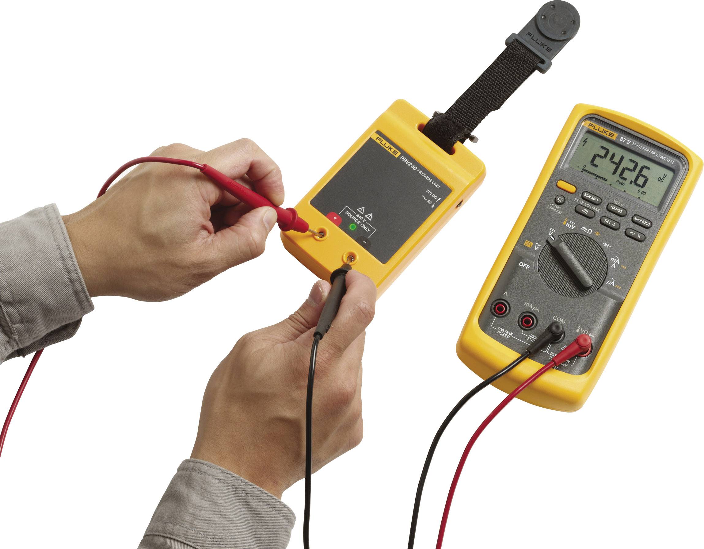 Een persoon gebruikt een geel digitaal multimeter om de spanning te meten aan een geel testapparaat dat 24,26 V aangeeft.