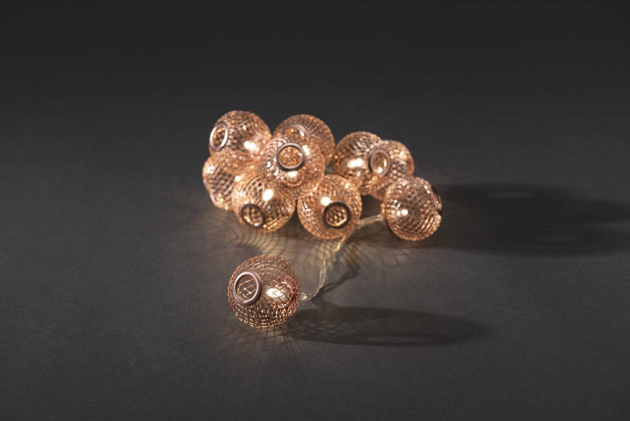 Ketting van koperkleurige lichtkogels op een zwarte achtergrond, stralend en decoratief gerangschikt.