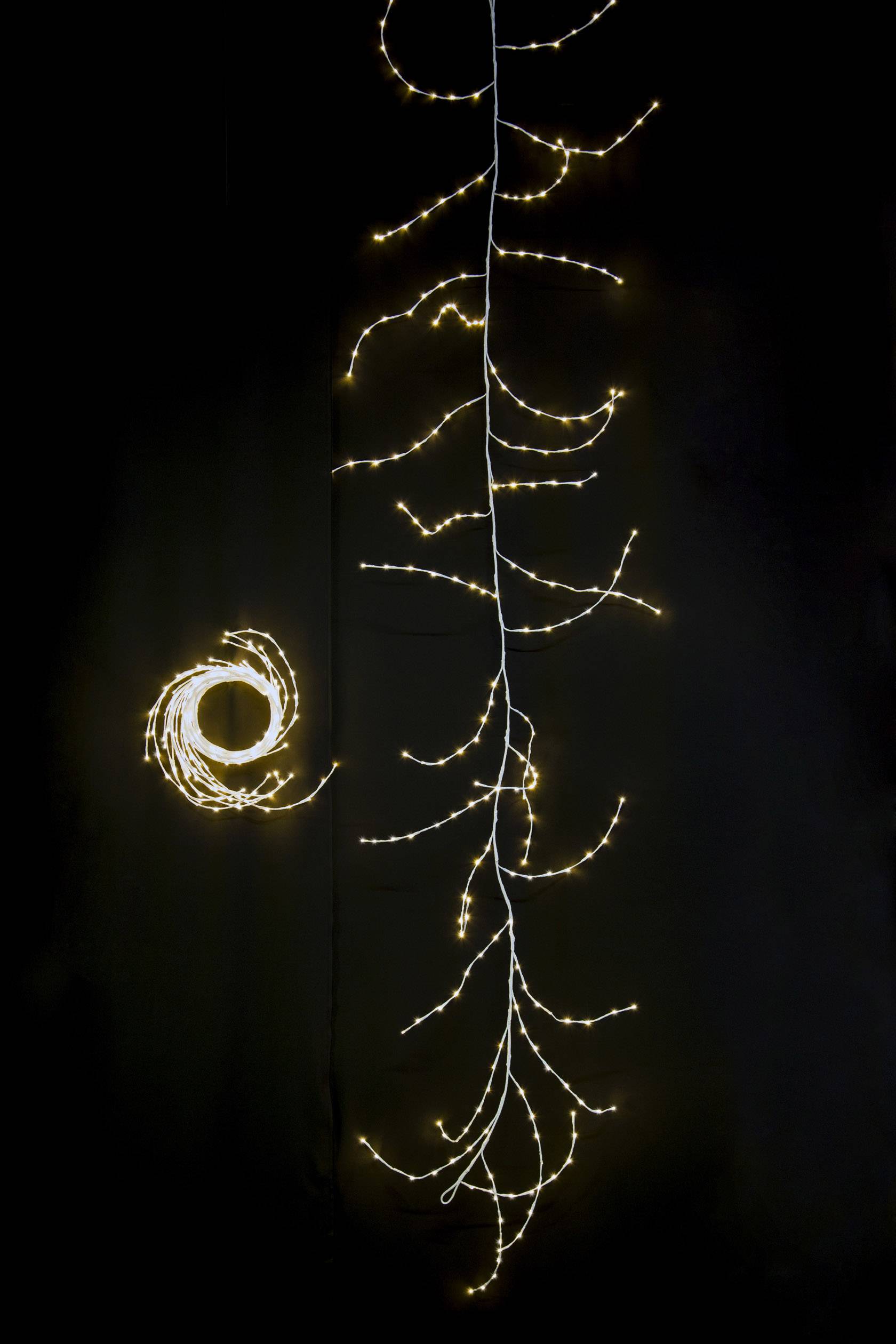 'Lichtketting in de vorm van een tak en een cirkel op een zwarte achtergrond, straalt een warme, gedempte gloed uit.'