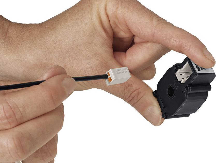Een hand houdt een elektrische sensor dicht bij een kabel met een stekker. De sensor staat op het punt om aangesloten te worden.