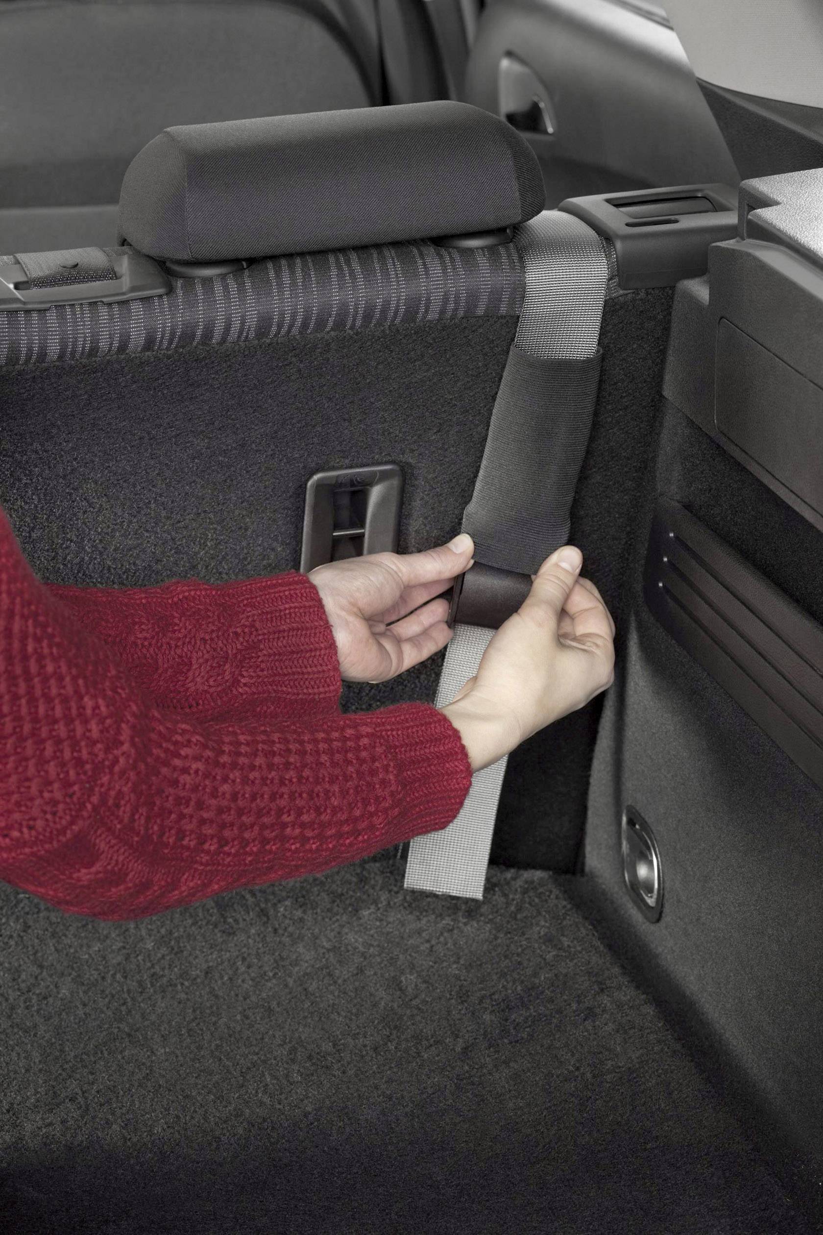 Een persoon houdt de veiligheidsgordel vast in het achterste gedeelte van een auto.