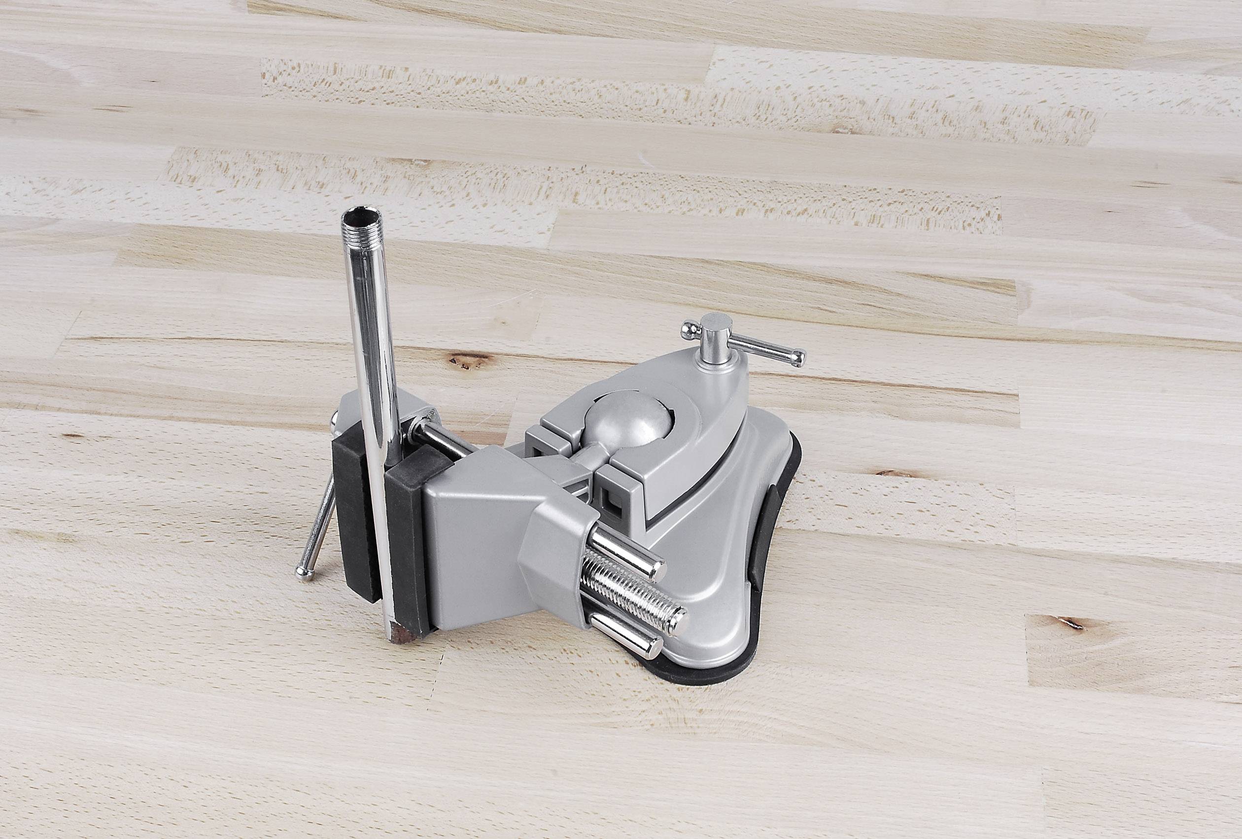 Grijze bankschroef op een lichte houten tafel. De bankschroef heeft een verstelbare houder en is bedoeld voor het vastklemmen van werkstukken.