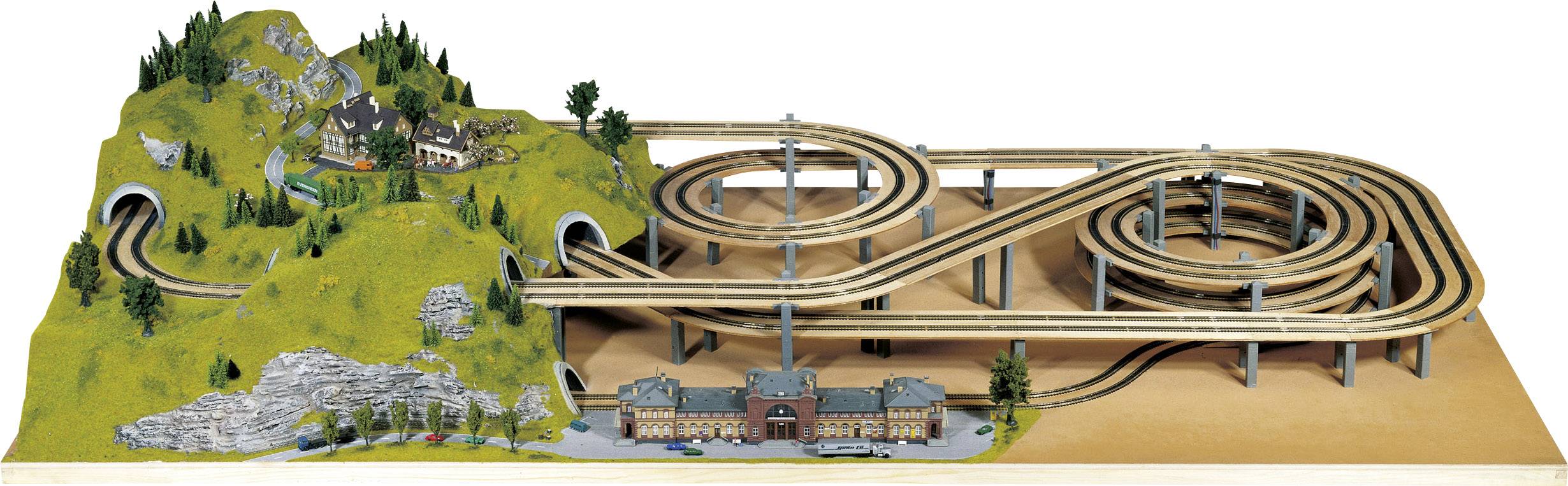 Modelspoorbaan met een meerlaags houten traject, tunnels en landschap met modelhuizen en bomen; onderaan een stationsscène.