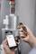 Een persoon houdt een digitale thermometer en een smartphone met een temperatuurmeetapp vast. Display: '30,1 graden'.