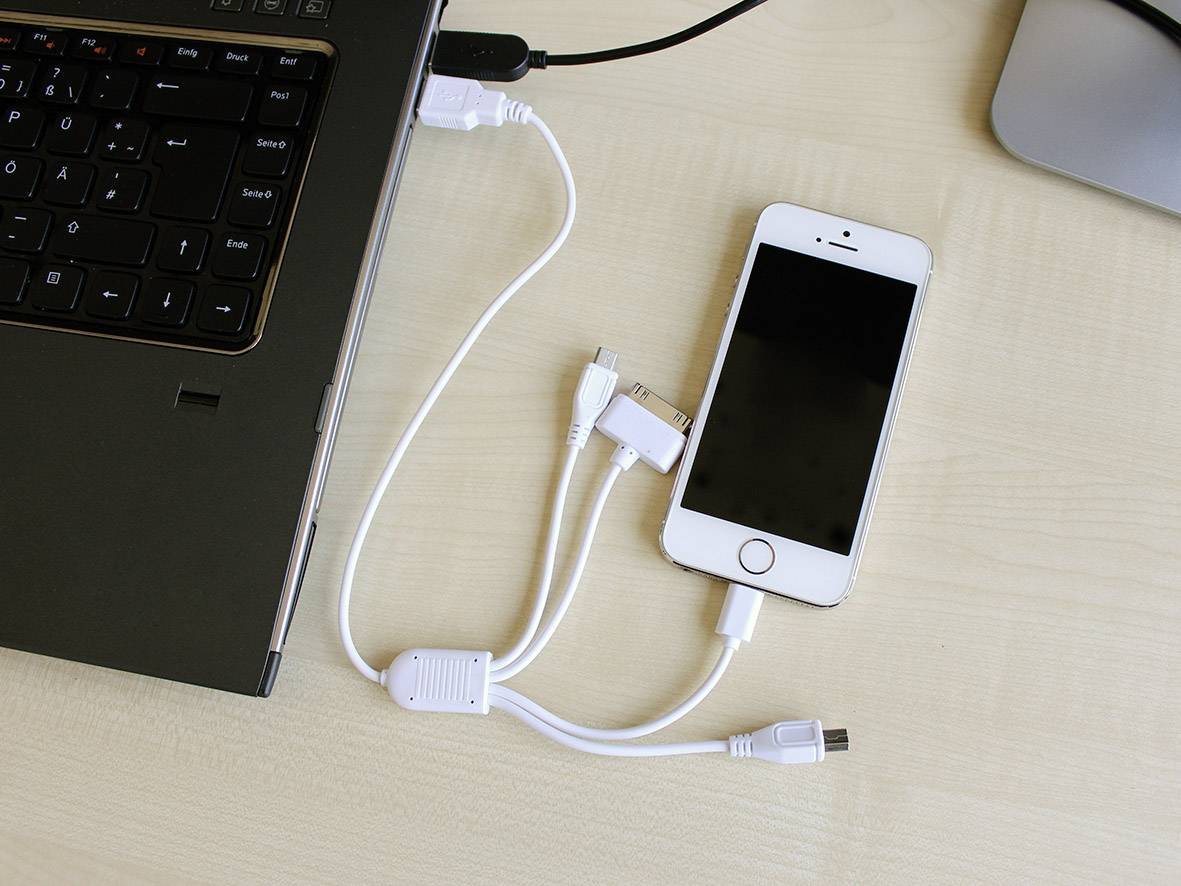 Een smartphone die via een multikabel is verbonden met een laptop op een bureau, toont geavanceerde connectiviteit.
